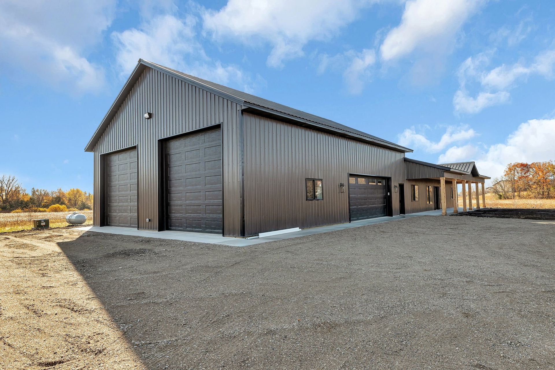 A large metal building with a garage and a house in the background.