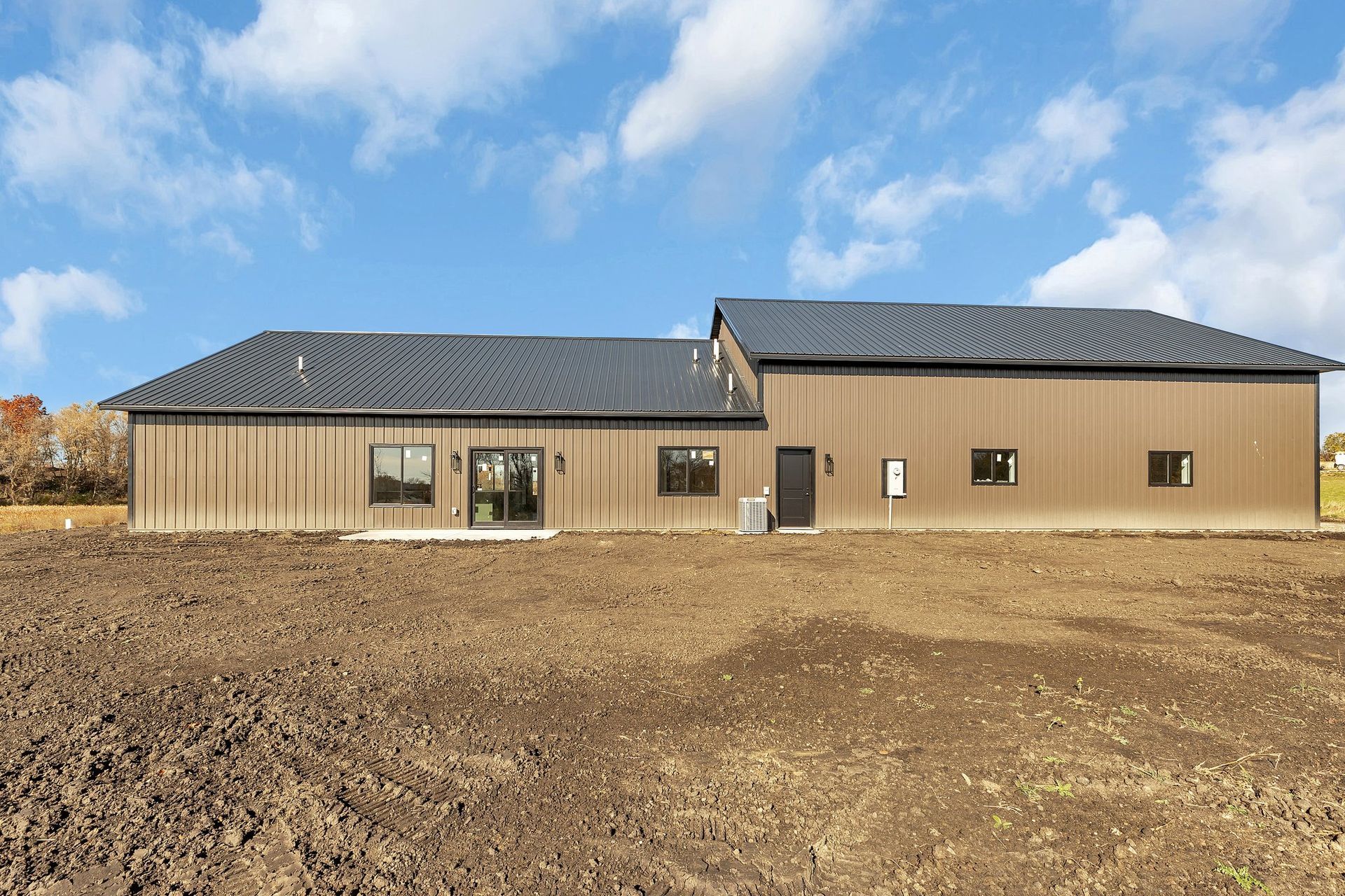 A large house is sitting in the middle of a dirt field.