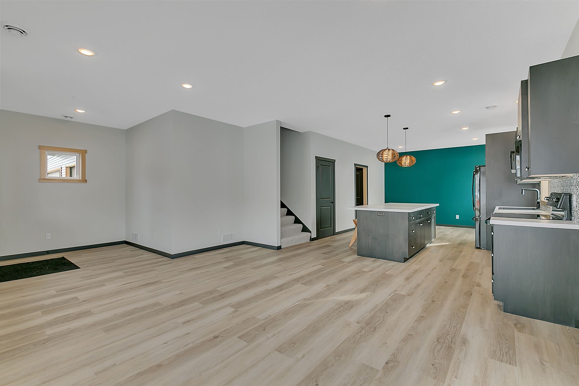 A large empty room with hardwood floors and a kitchen.