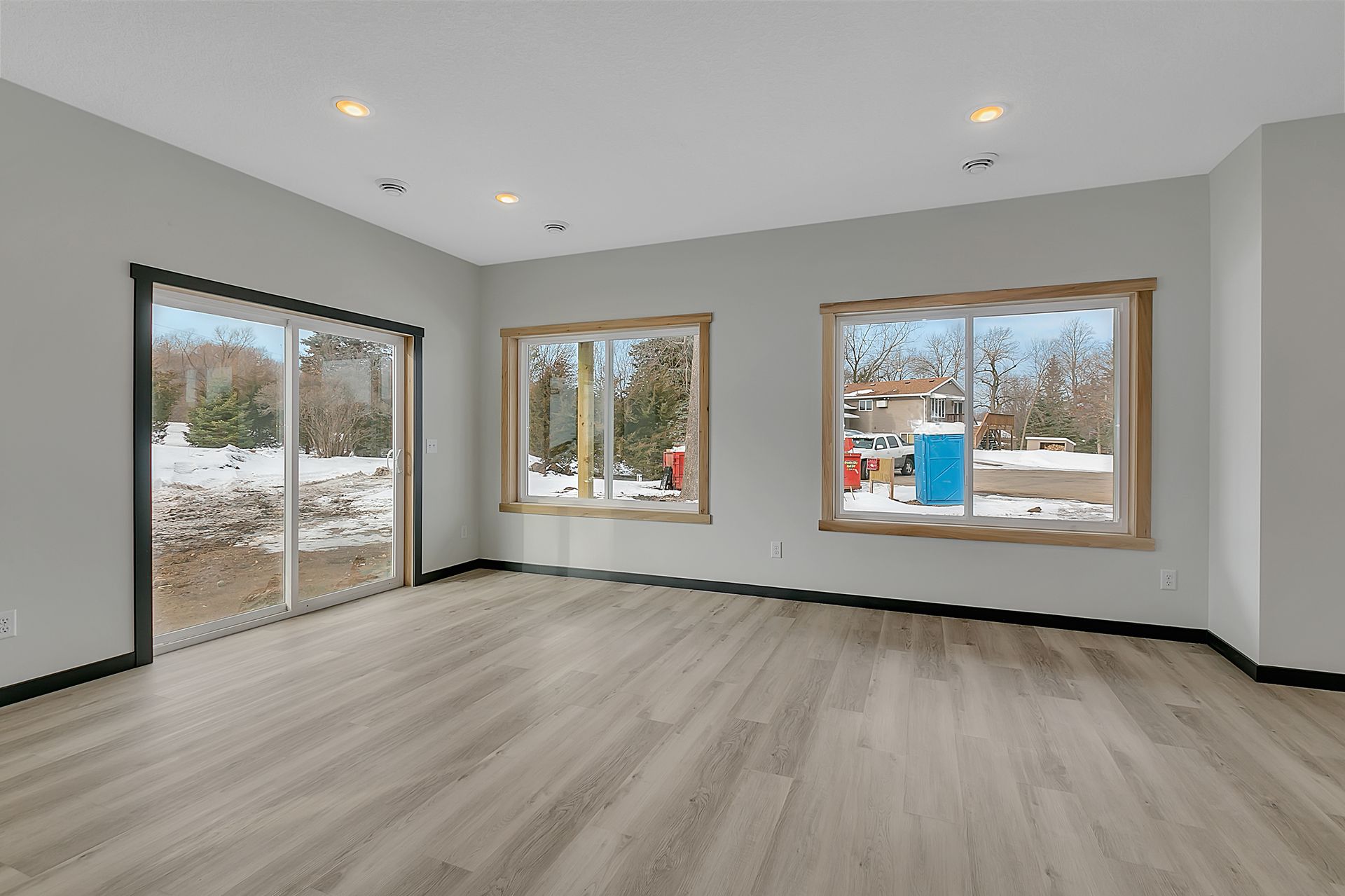 An empty living room with hardwood floors and sliding glass doors.