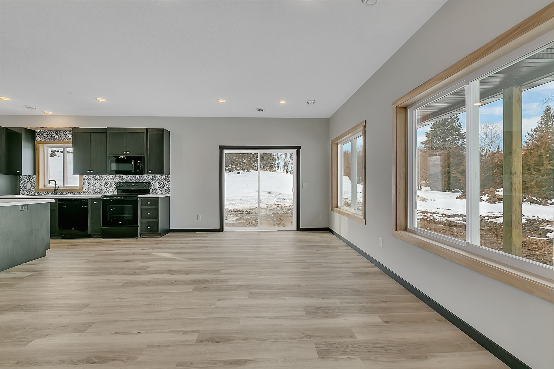 A large empty room with a kitchen and a lot of windows.