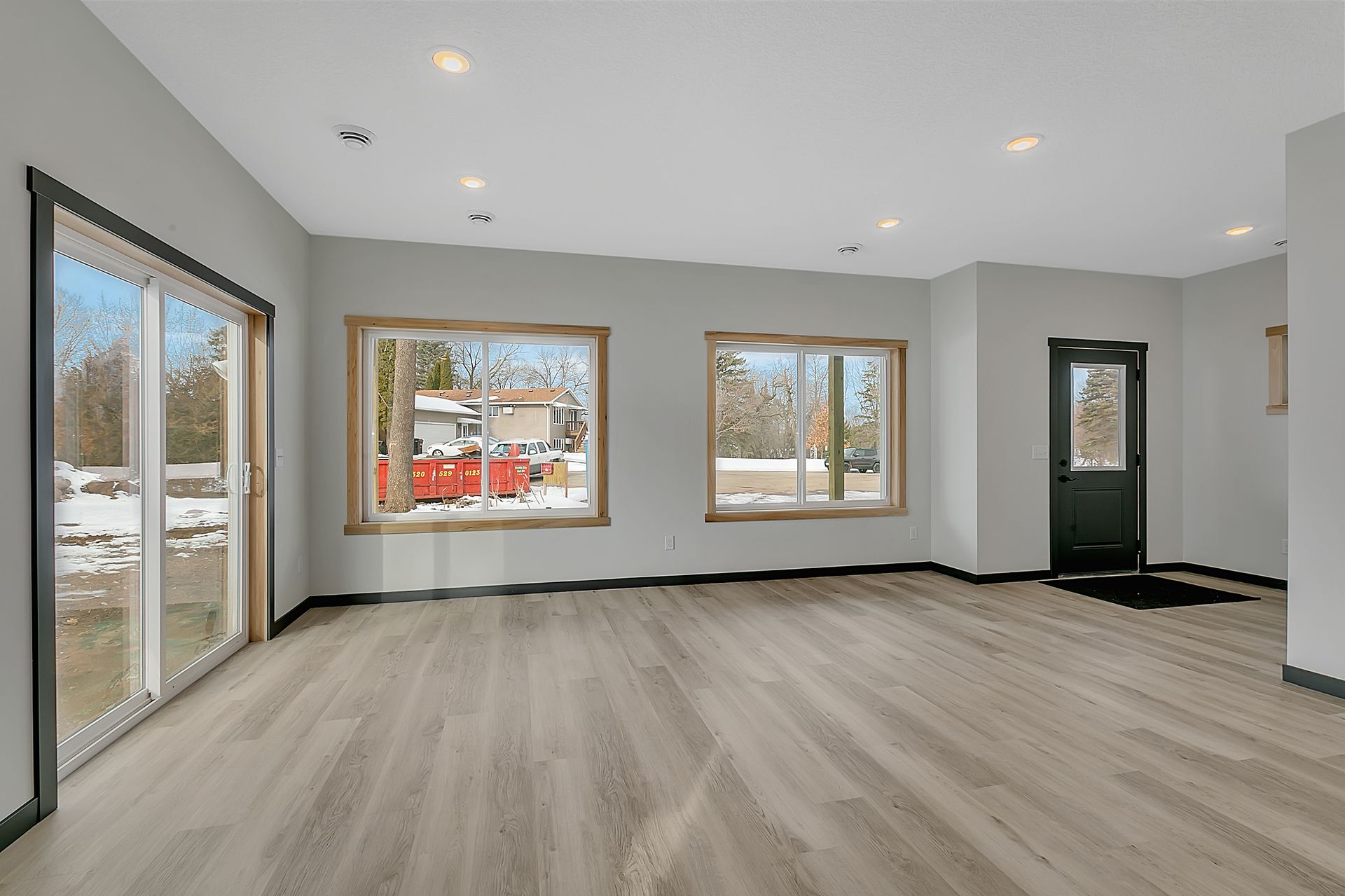An empty living room with hardwood floors and lots of windows