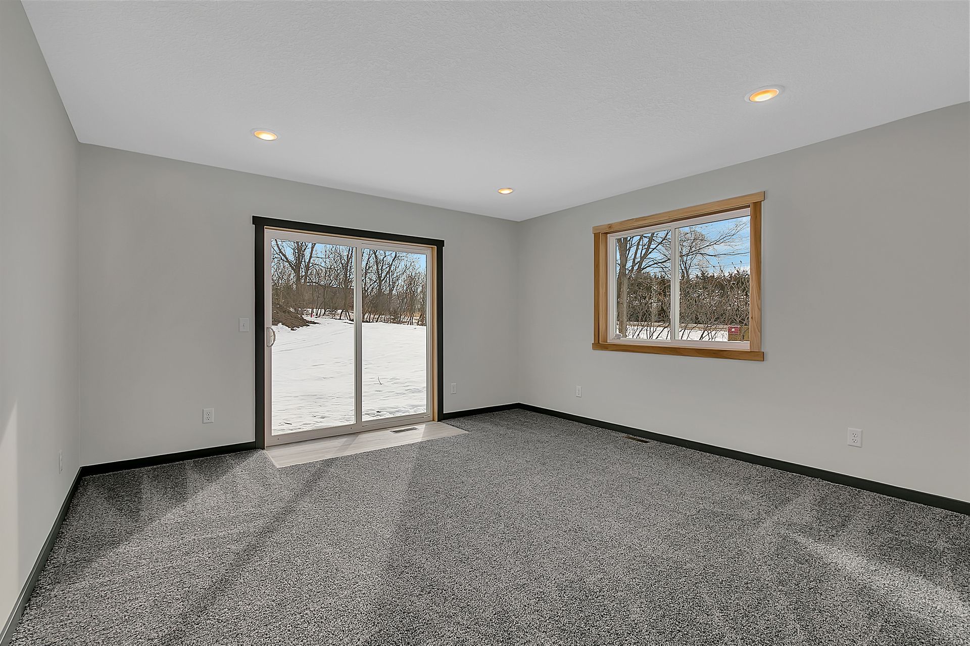 An empty room with a sliding glass door and two windows.