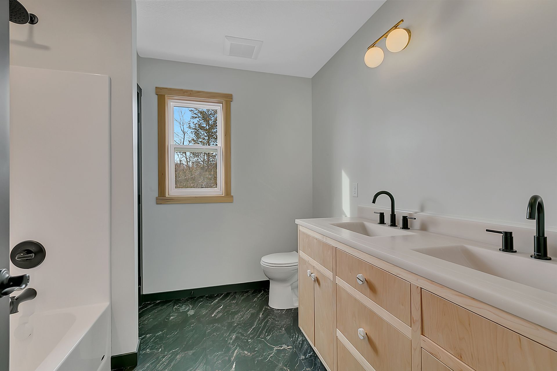 A bathroom with two sinks a toilet and a window