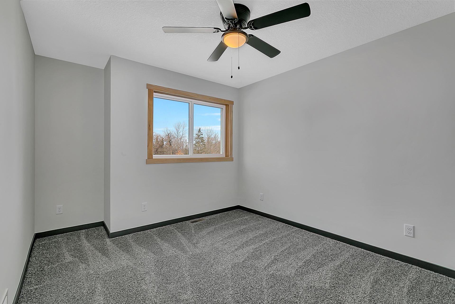 An empty bedroom with a ceiling fan and a window.