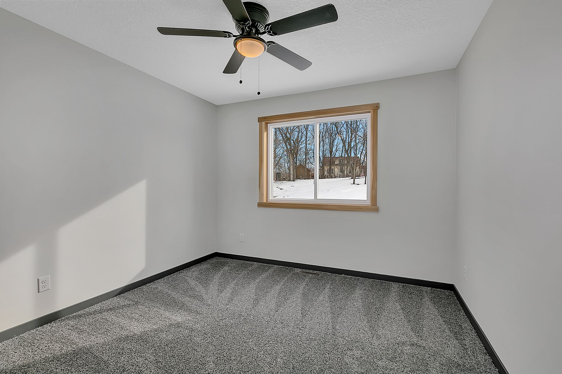 An empty bedroom with a ceiling fan and a window.