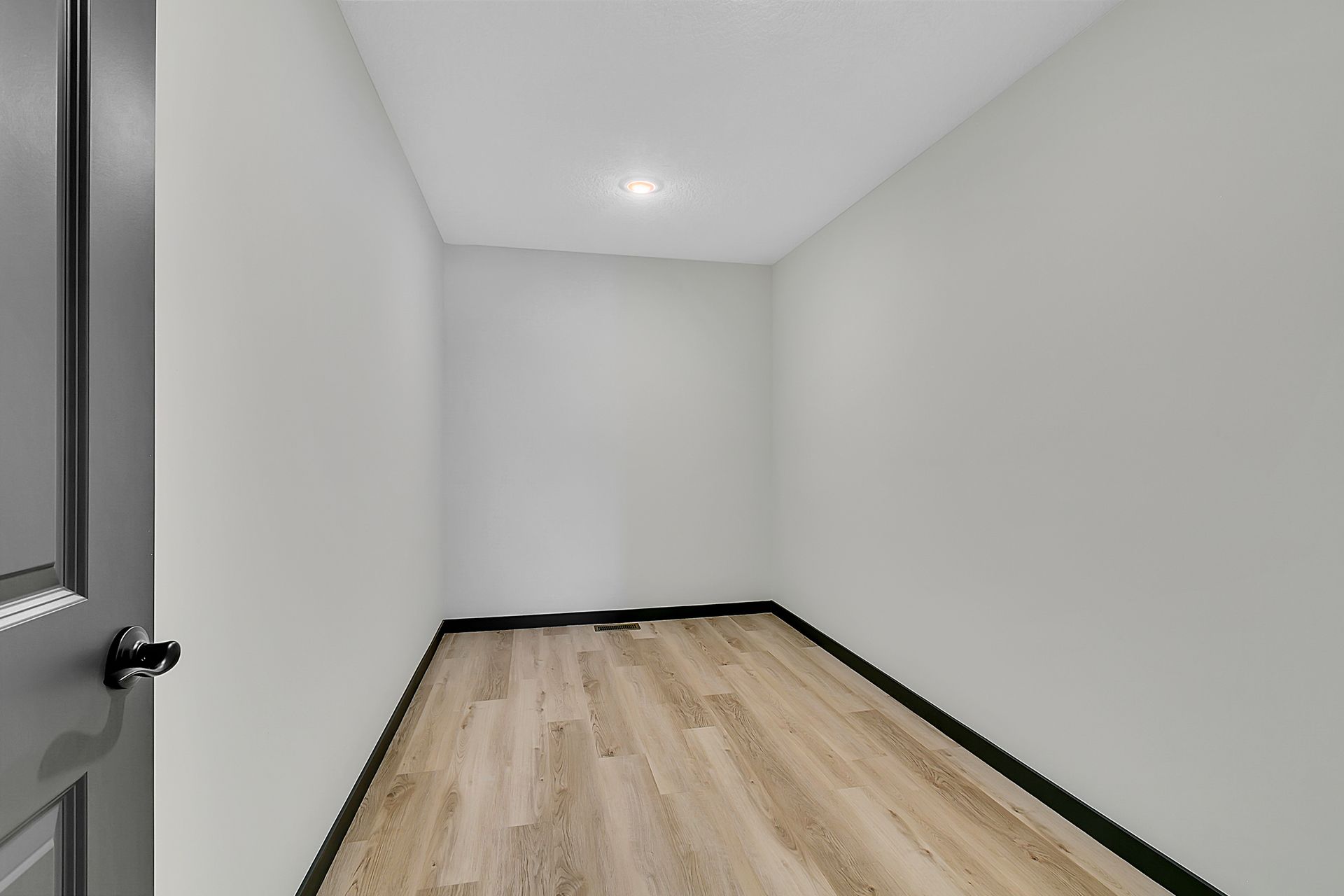 An empty room with hardwood floors and white walls.
