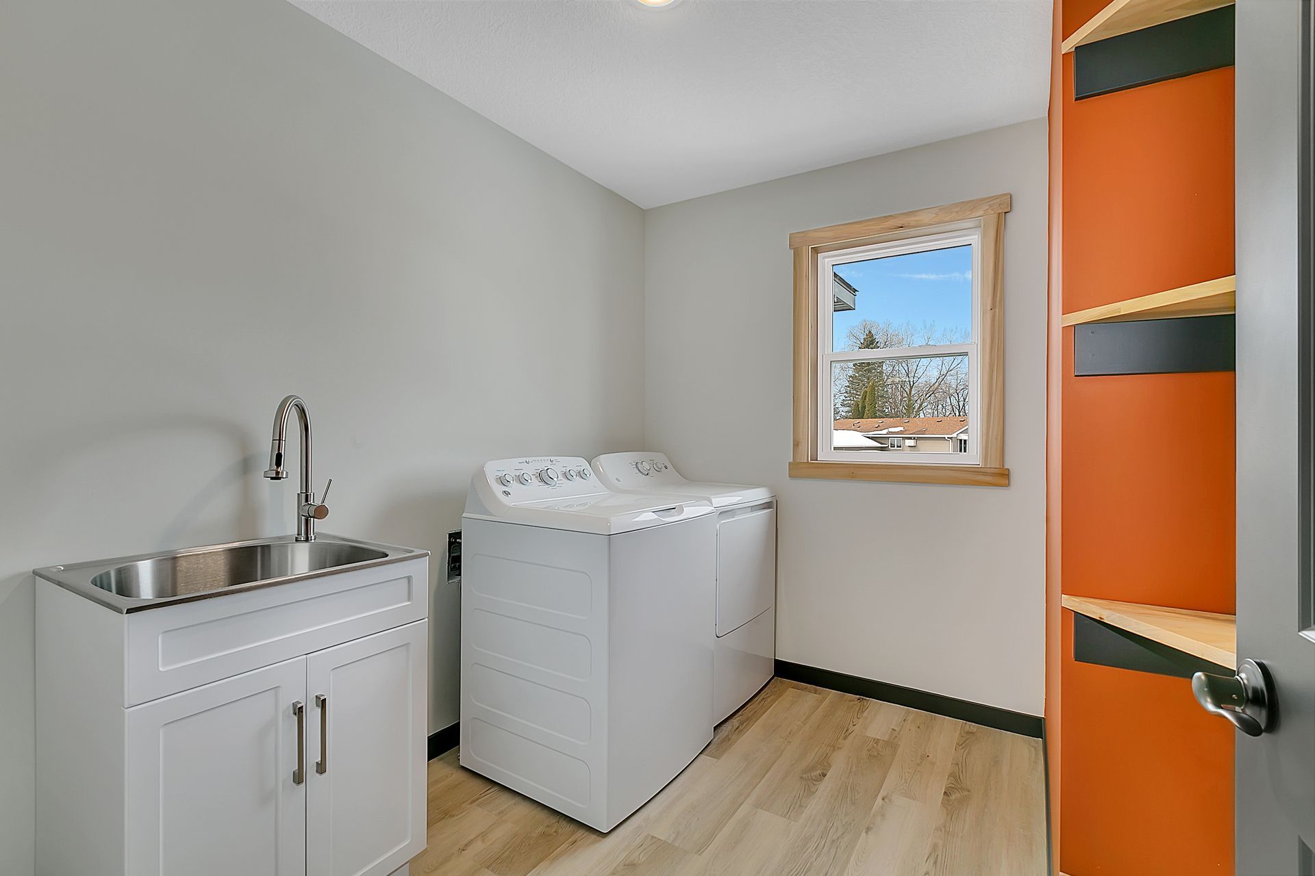 A laundry room with a washer and dryer , sink , and window.
