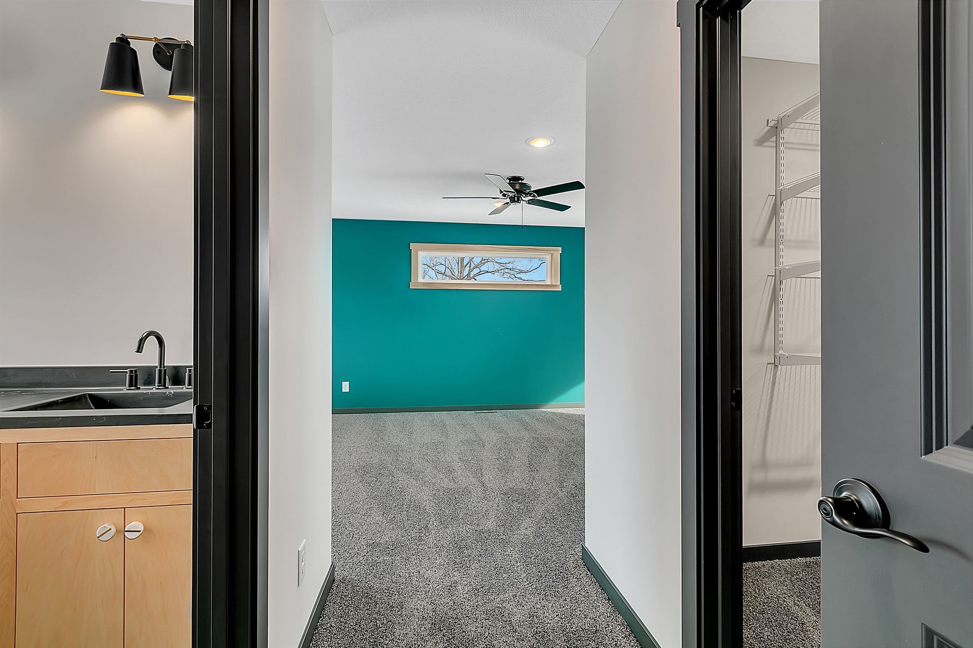 A hallway in a house with a blue wall and a ceiling fan.
