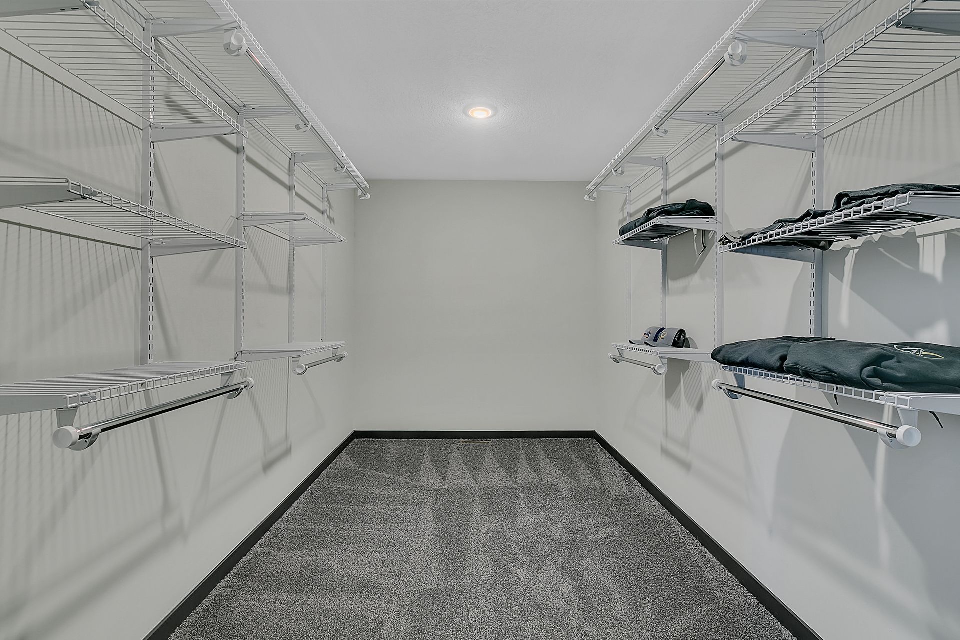 A walk in closet with a lot of shelves and clothes on them.