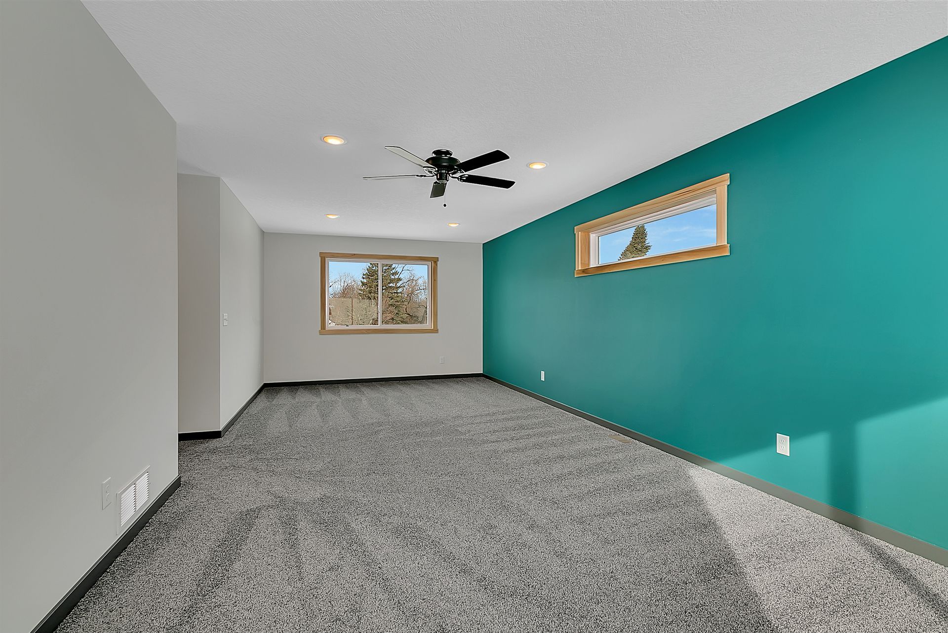 An empty room with a ceiling fan and a window.