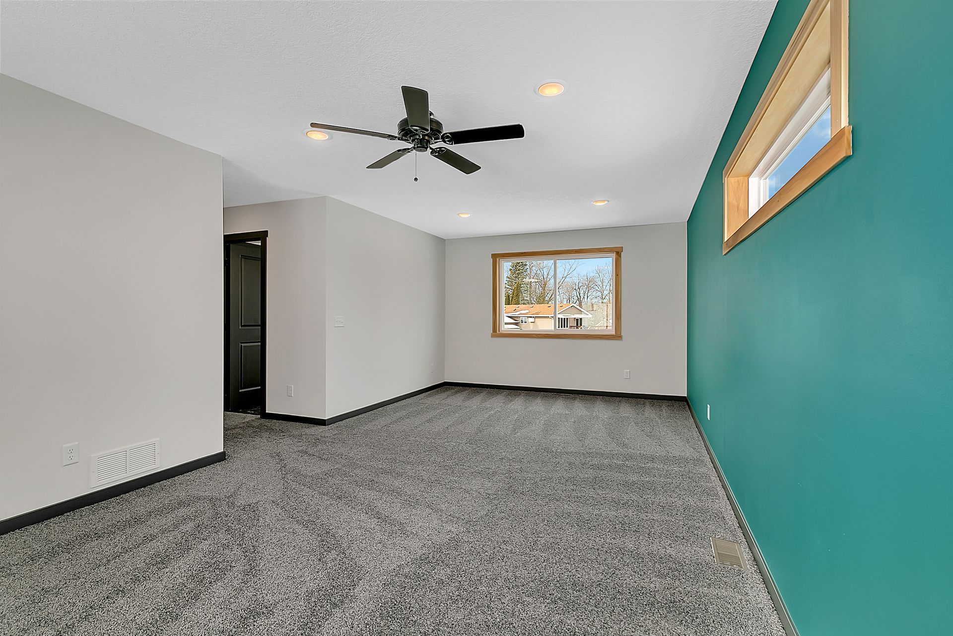 An empty room with a ceiling fan and a window.