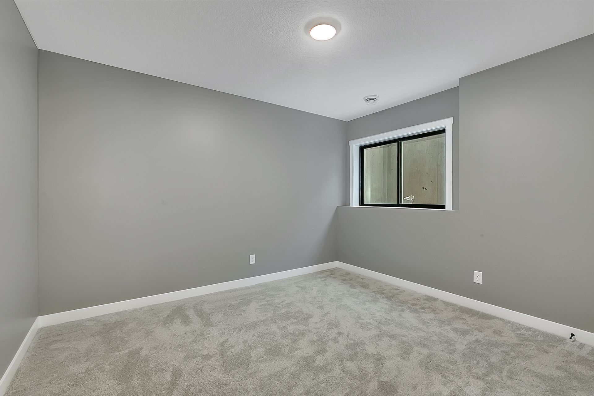 An empty room with gray walls and a window.