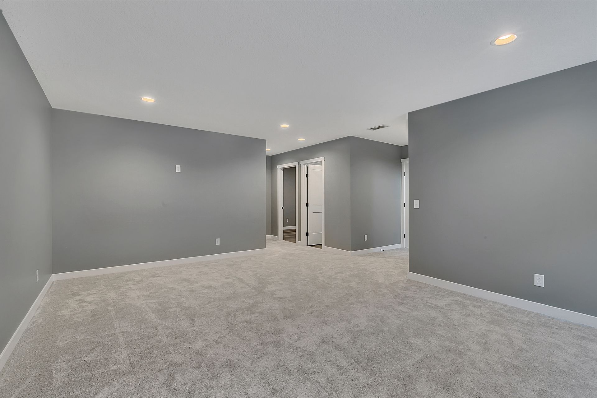 An empty basement with gray walls and carpet.