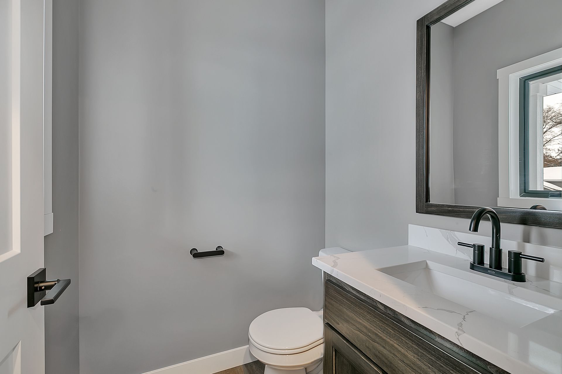 A bathroom with a toilet , sink and mirror.