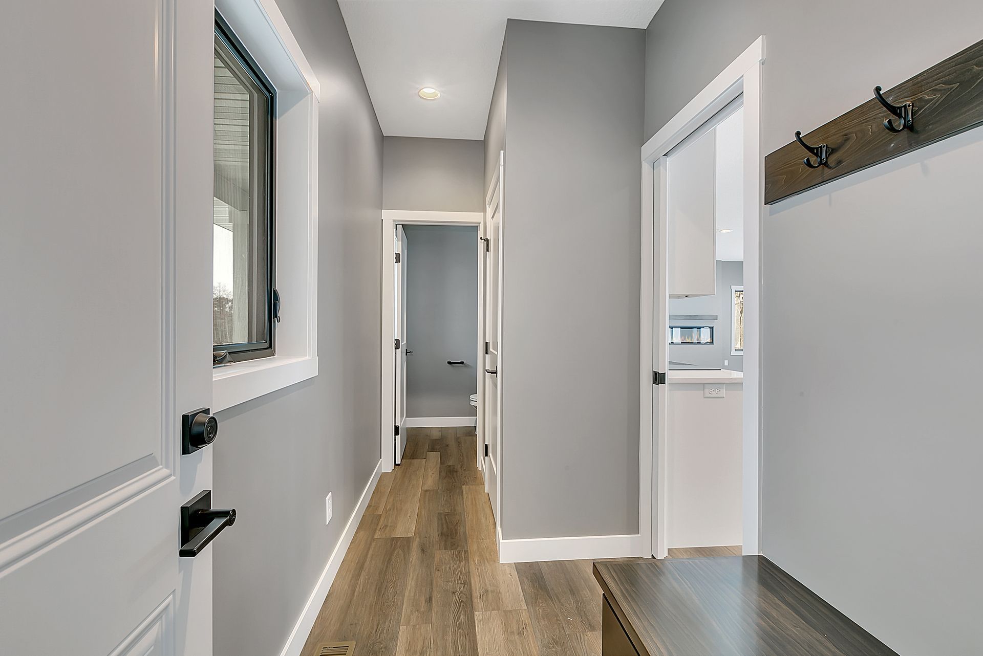 A hallway in a house with a bench and a window.