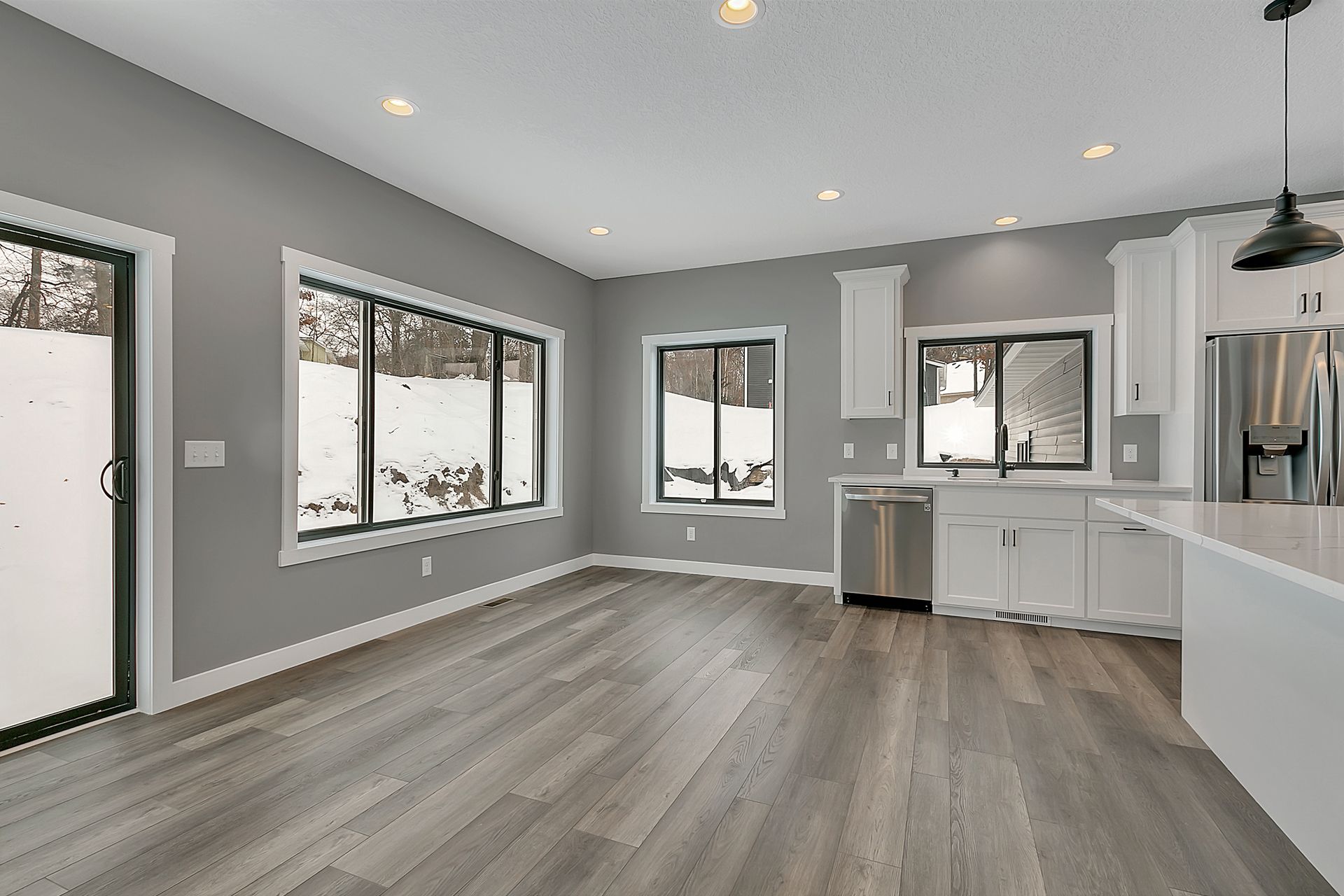 An empty kitchen with a lot of windows and hardwood floors.