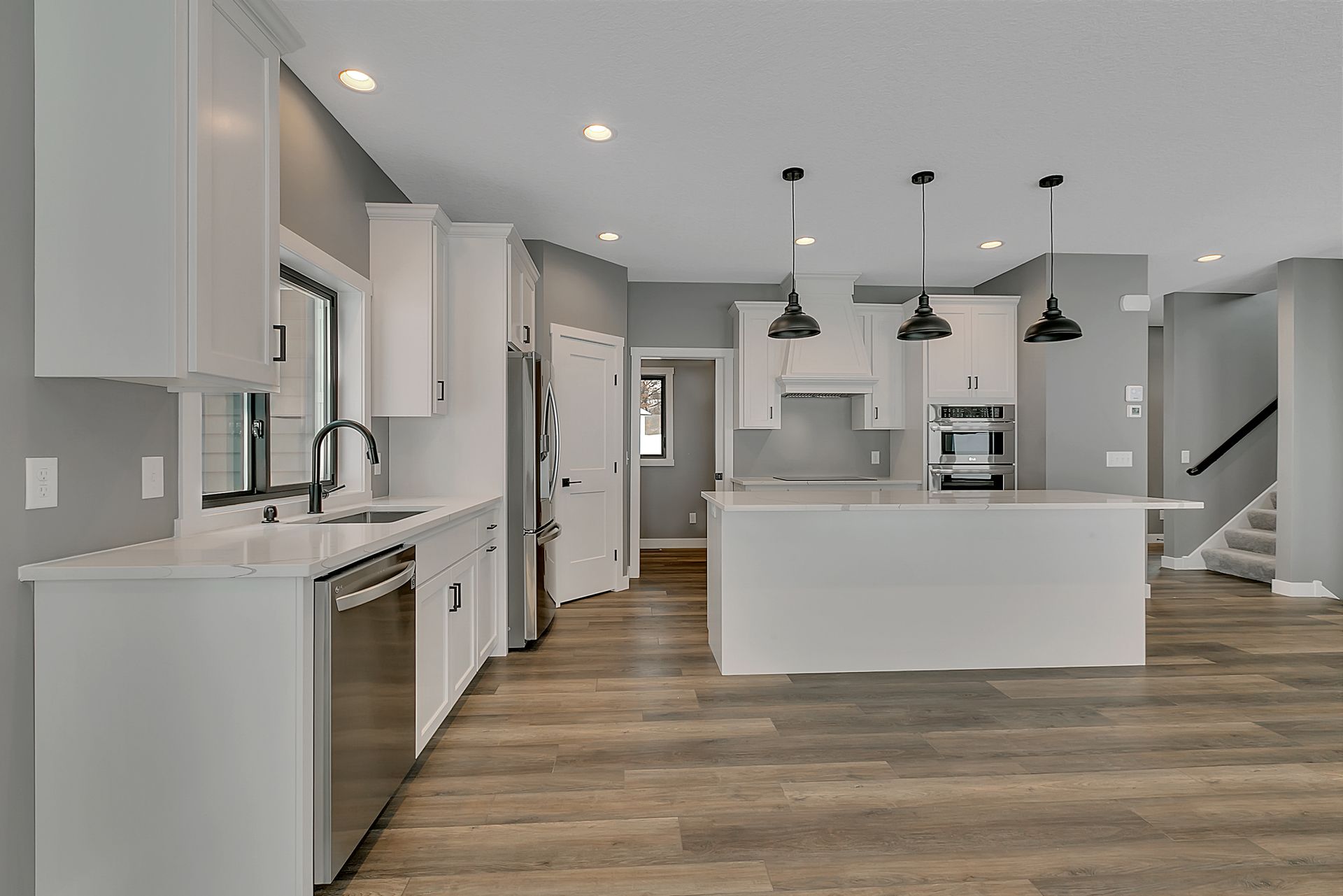 A kitchen with white cabinets , stainless steel appliances , and a large island.