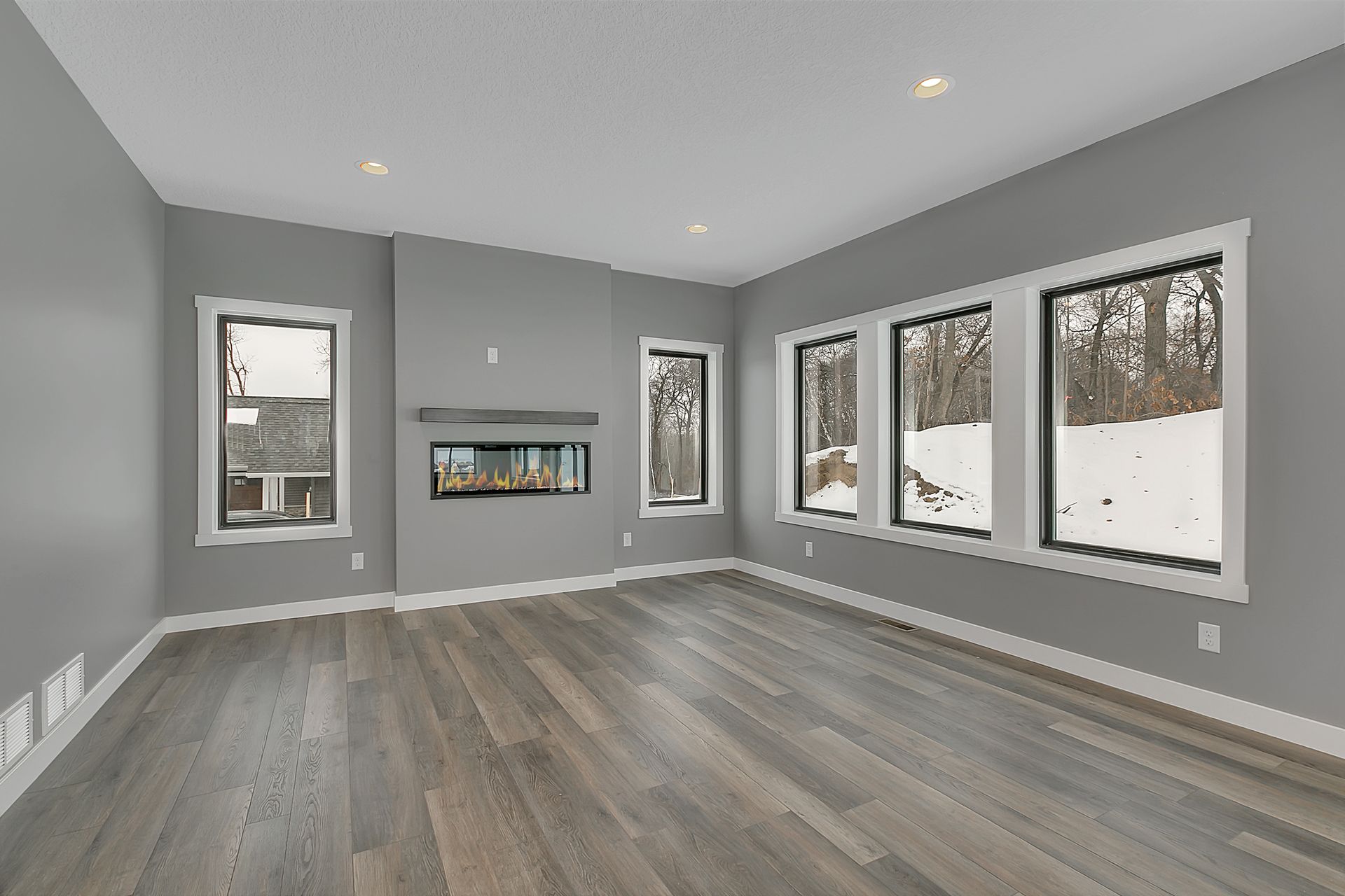 An empty living room with a fireplace and lots of windows.