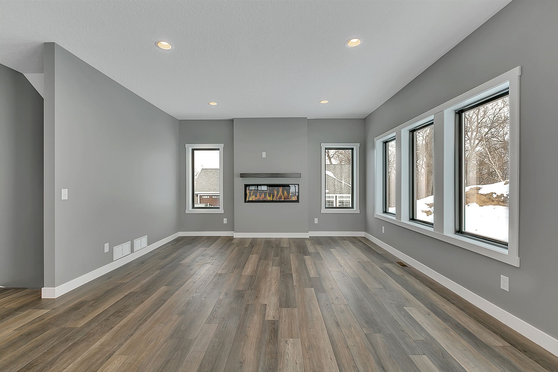 An empty living room with a fireplace and lots of windows
