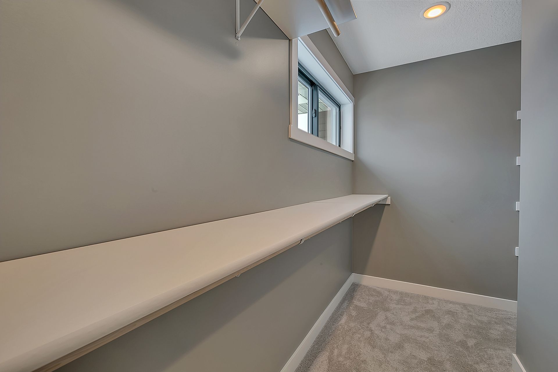 An empty walk in closet with a window and shelves.
