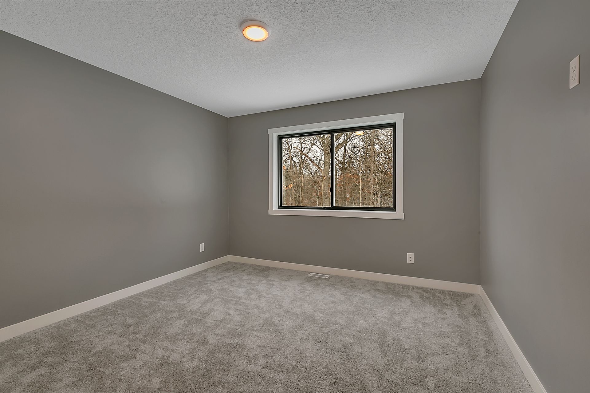 An empty room with a window and a carpeted floor.