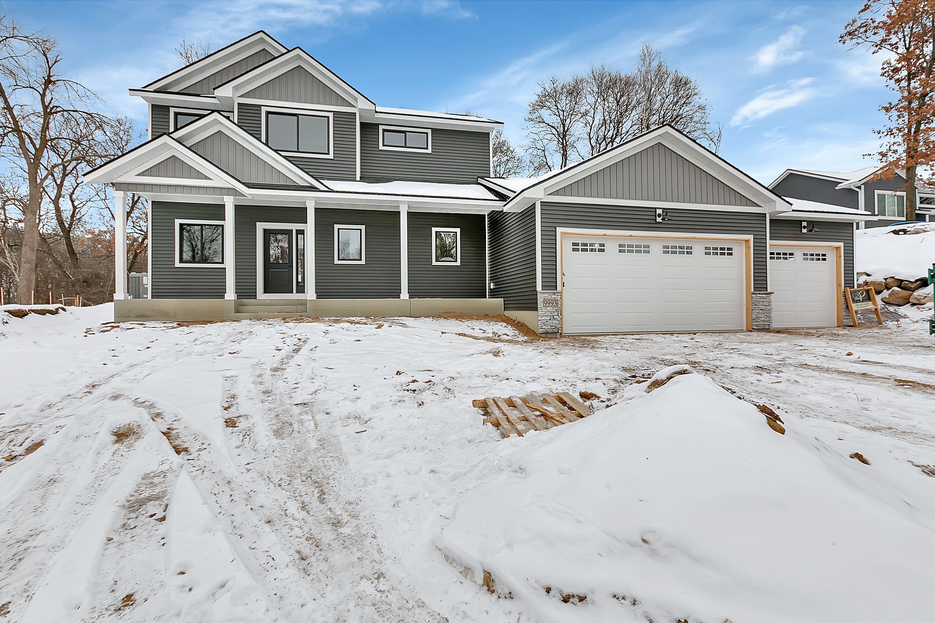 A large house with two garages is covered in snow.