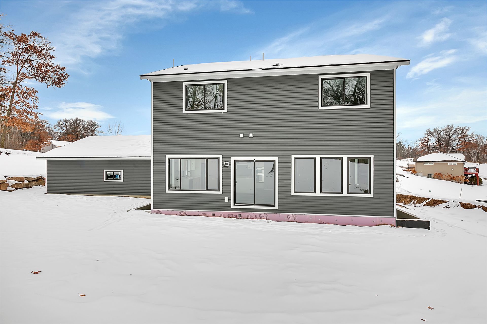 A house with a lot of windows is covered in snow.