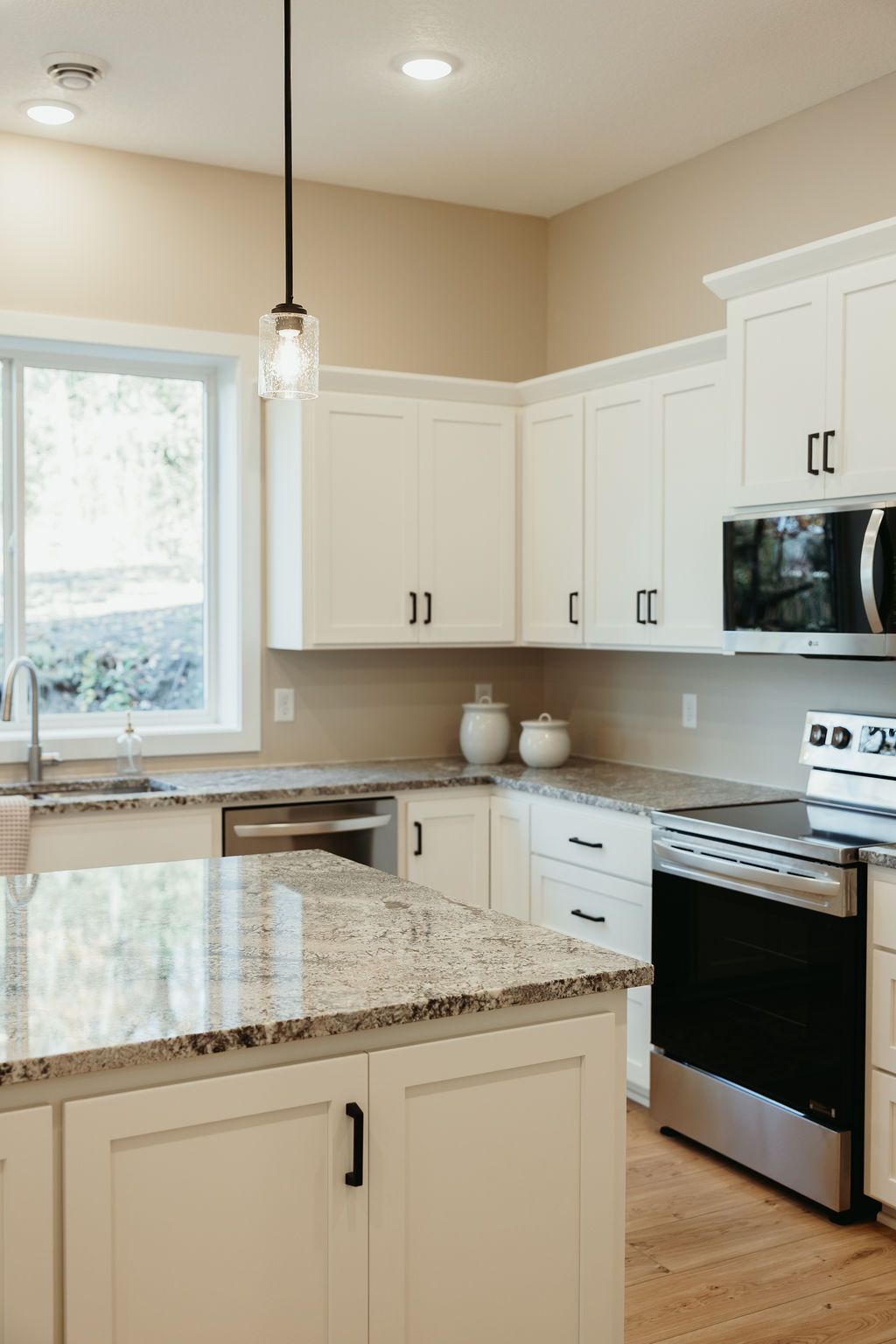 White kitchen with granite countertops, stainless steel appliances, and island.