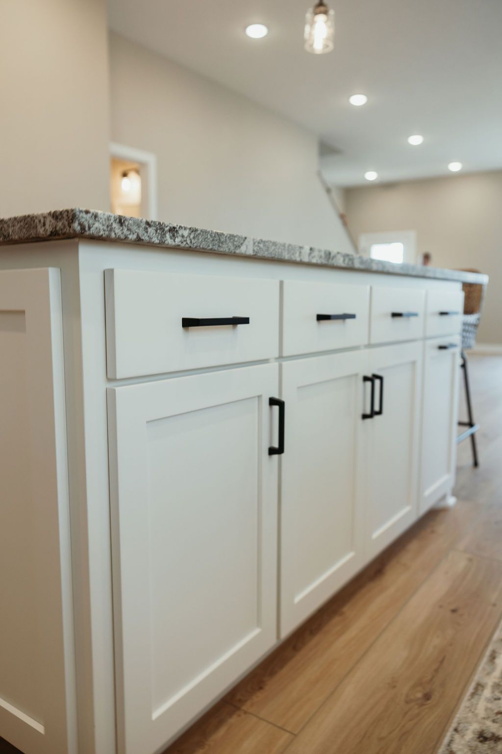 White kitchen island with granite countertop and black hardware.