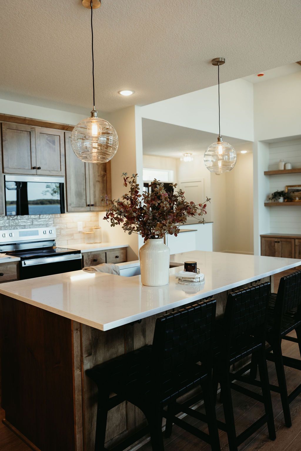 Modern kitchen with a white countertop island, pendant lights, and wooden cabinets.