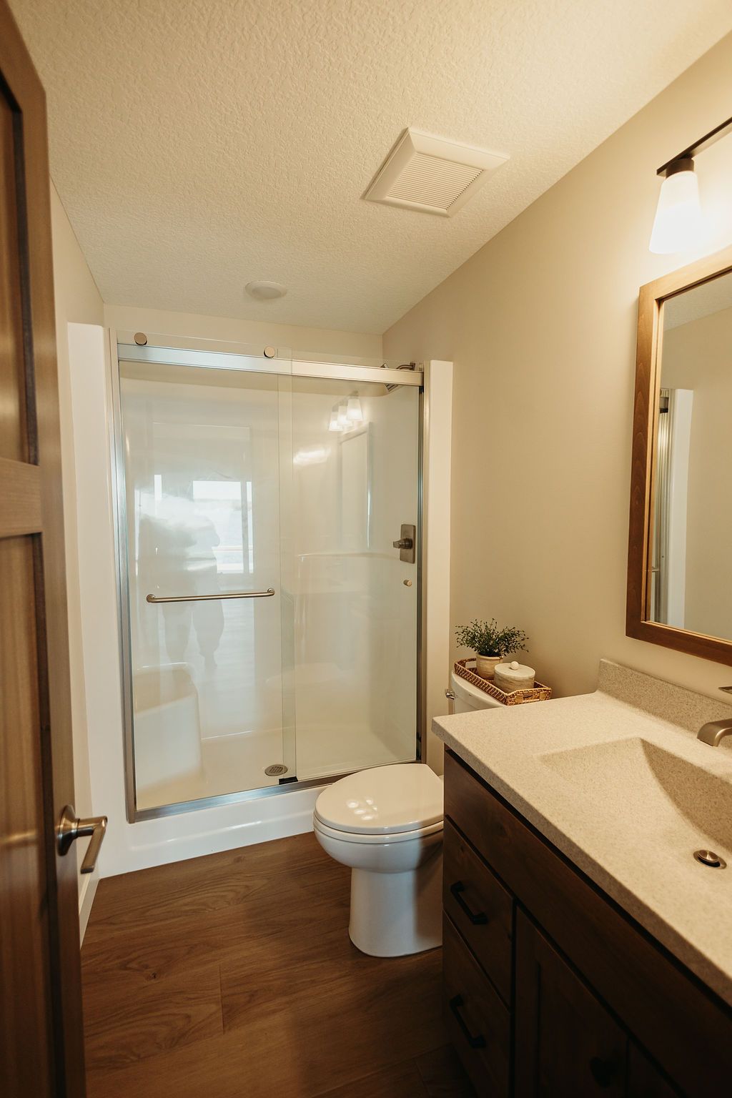 Small bathroom with dark vanity, toilet, sink, and glass shower/tub enclosure.