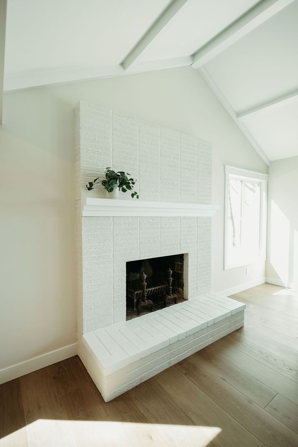 Bright white modern living room with a large fireplace and high sloped ceilings