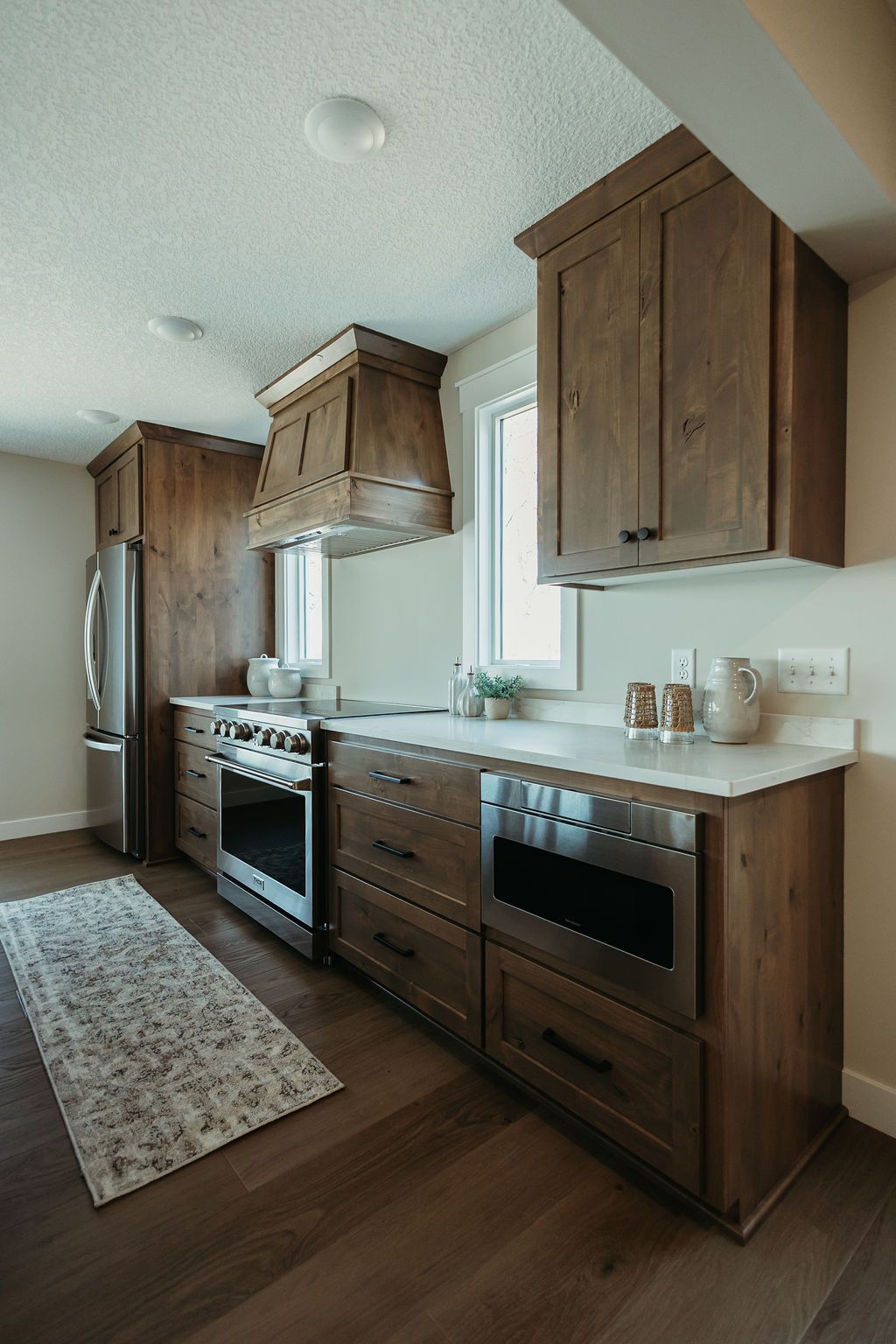 Modern kitchen with wood cabinets, stainless steel appliances, white countertops, and a window over the sink