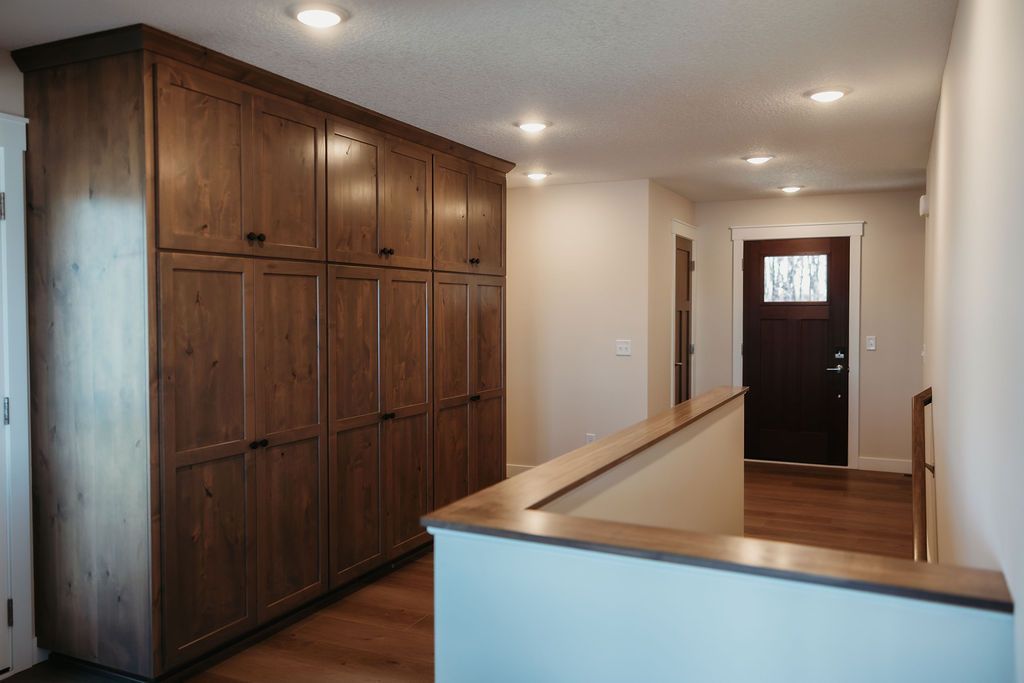Hallway with large wooden built-in cabinets, white walls, and a front door at the end.