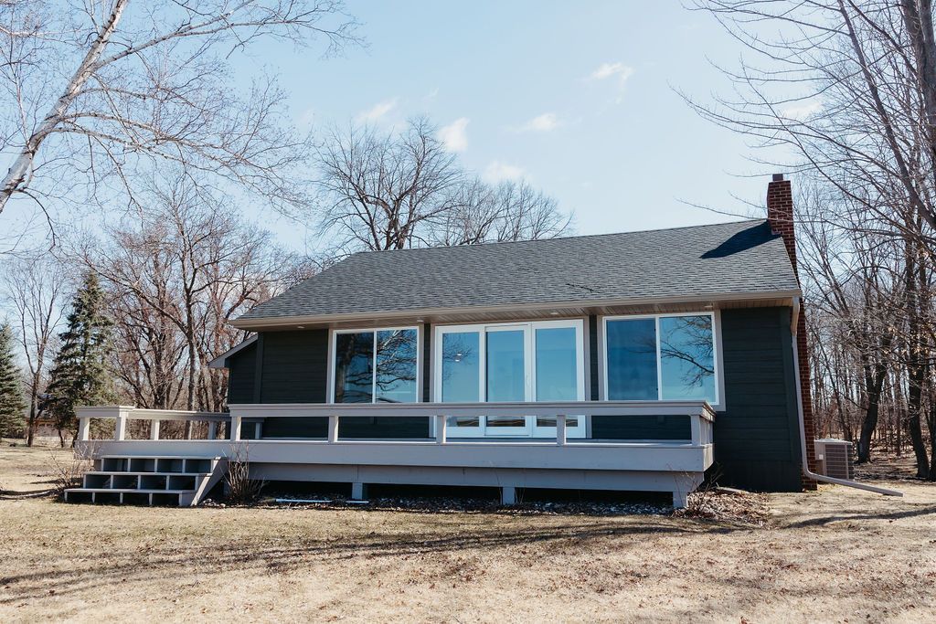 Small blue house with a front porch in a leafless rural yard under a clear sky