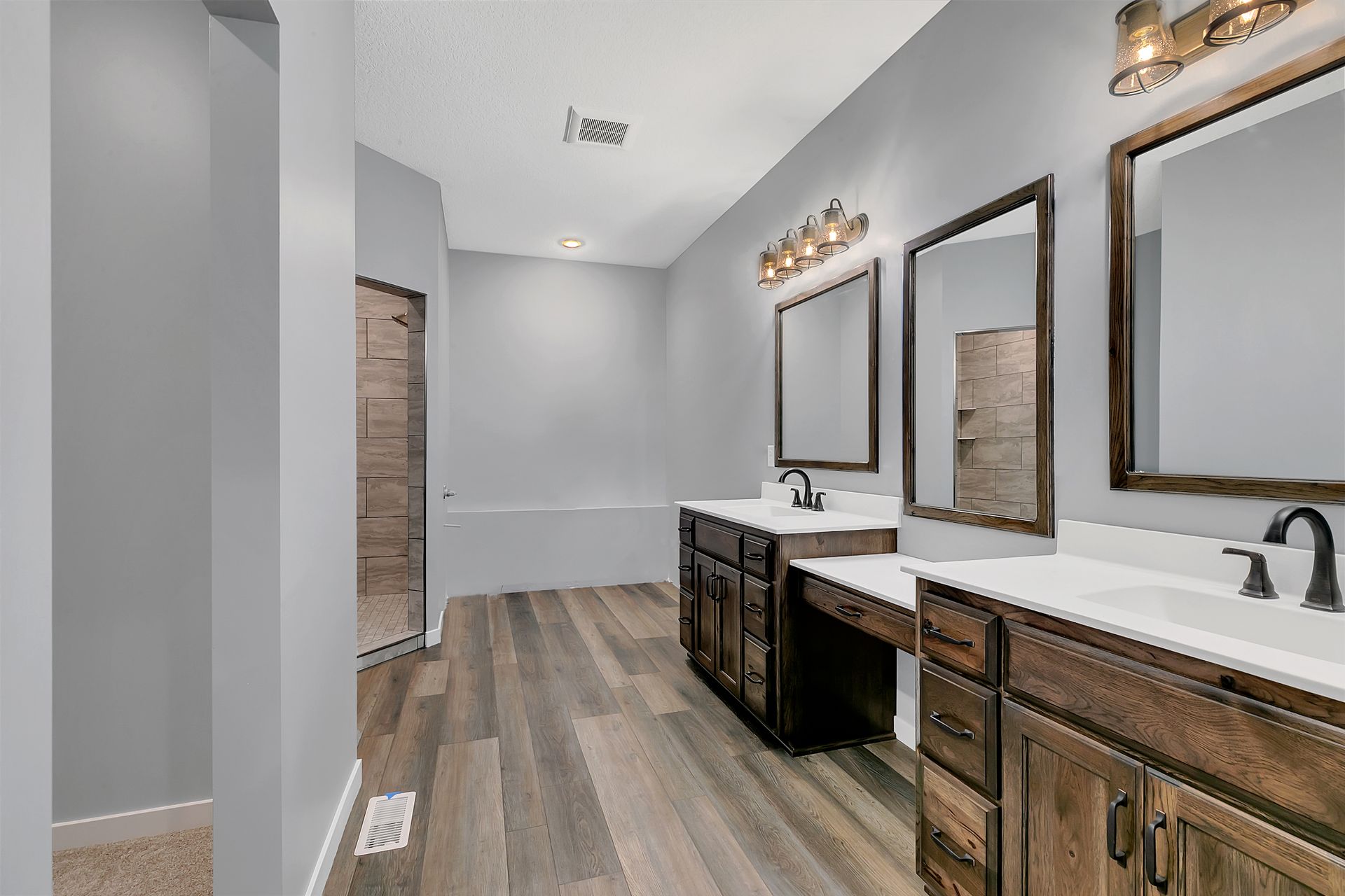 A bathroom with two sinks , two mirrors and a bathtub.