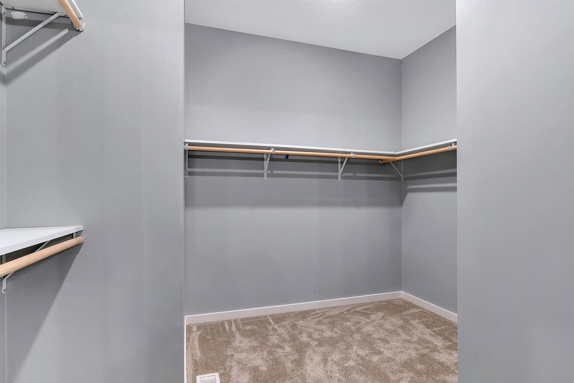 An empty walk in closet with gray walls and a brown carpet.