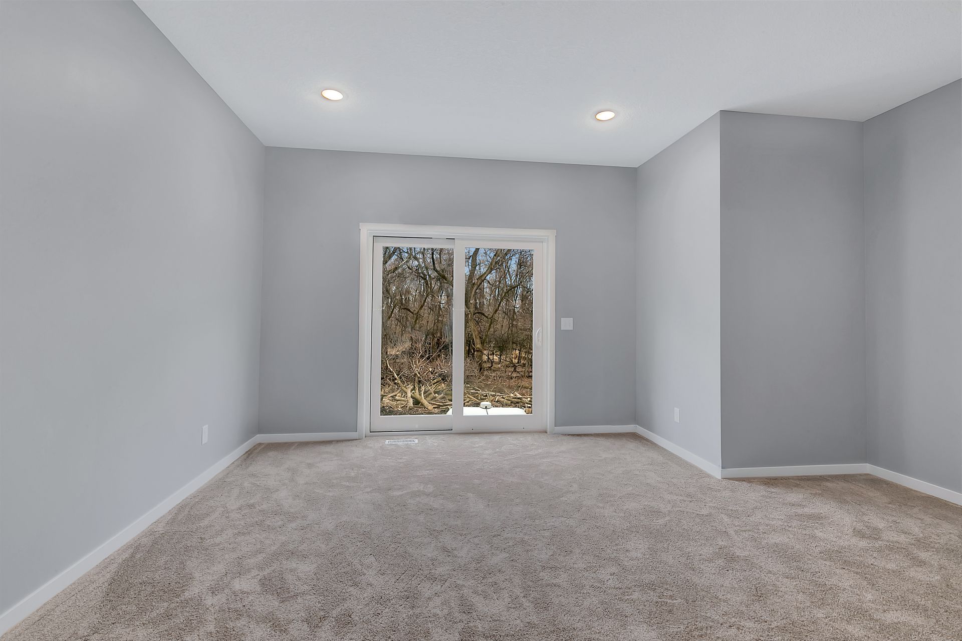 An empty room with a sliding glass door and a window.