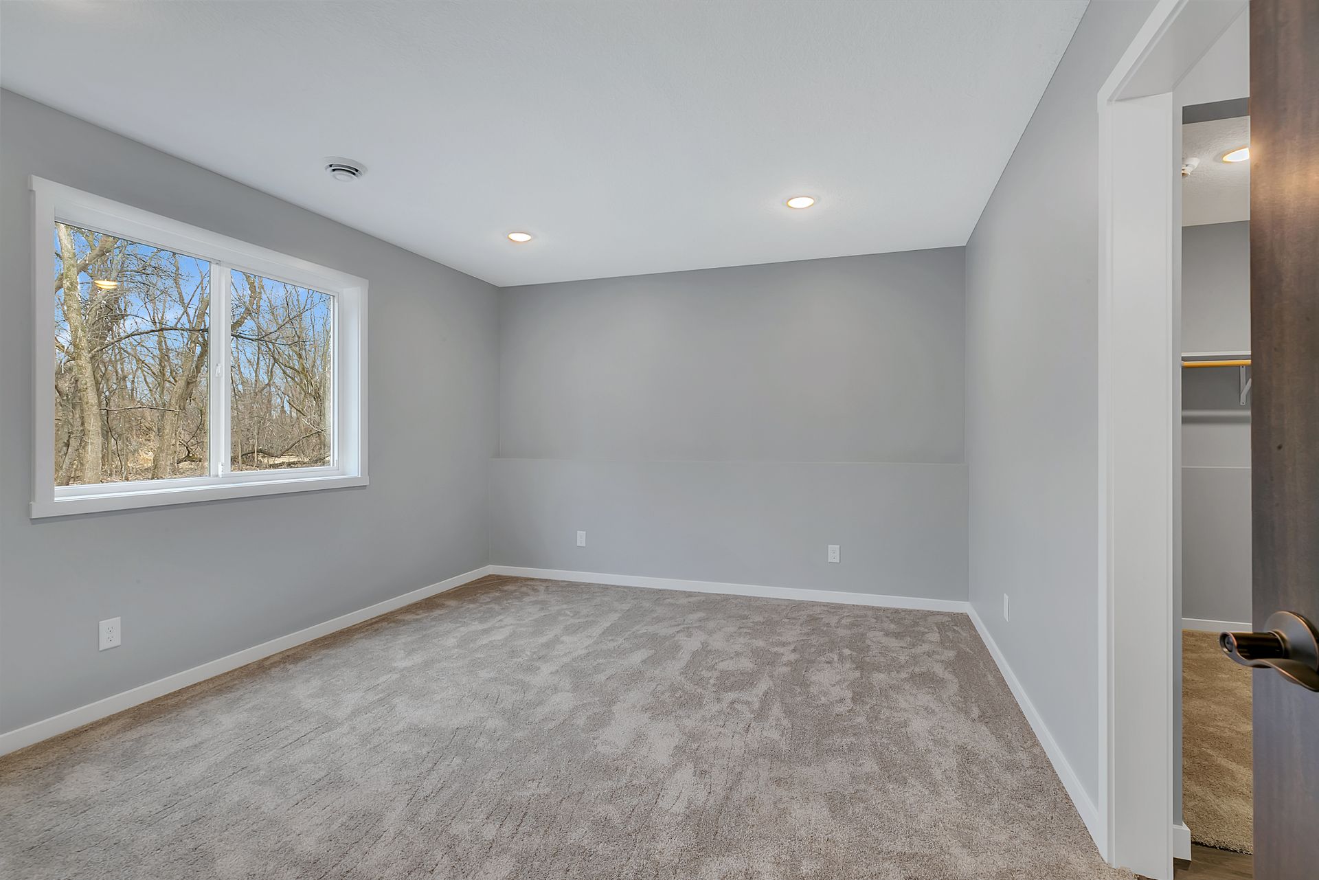An empty room with a carpeted floor and a window.