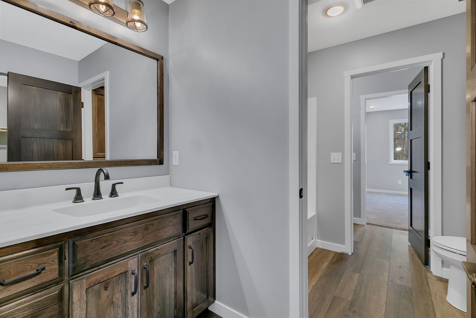 A bathroom with a sink , mirror and wooden cabinets.