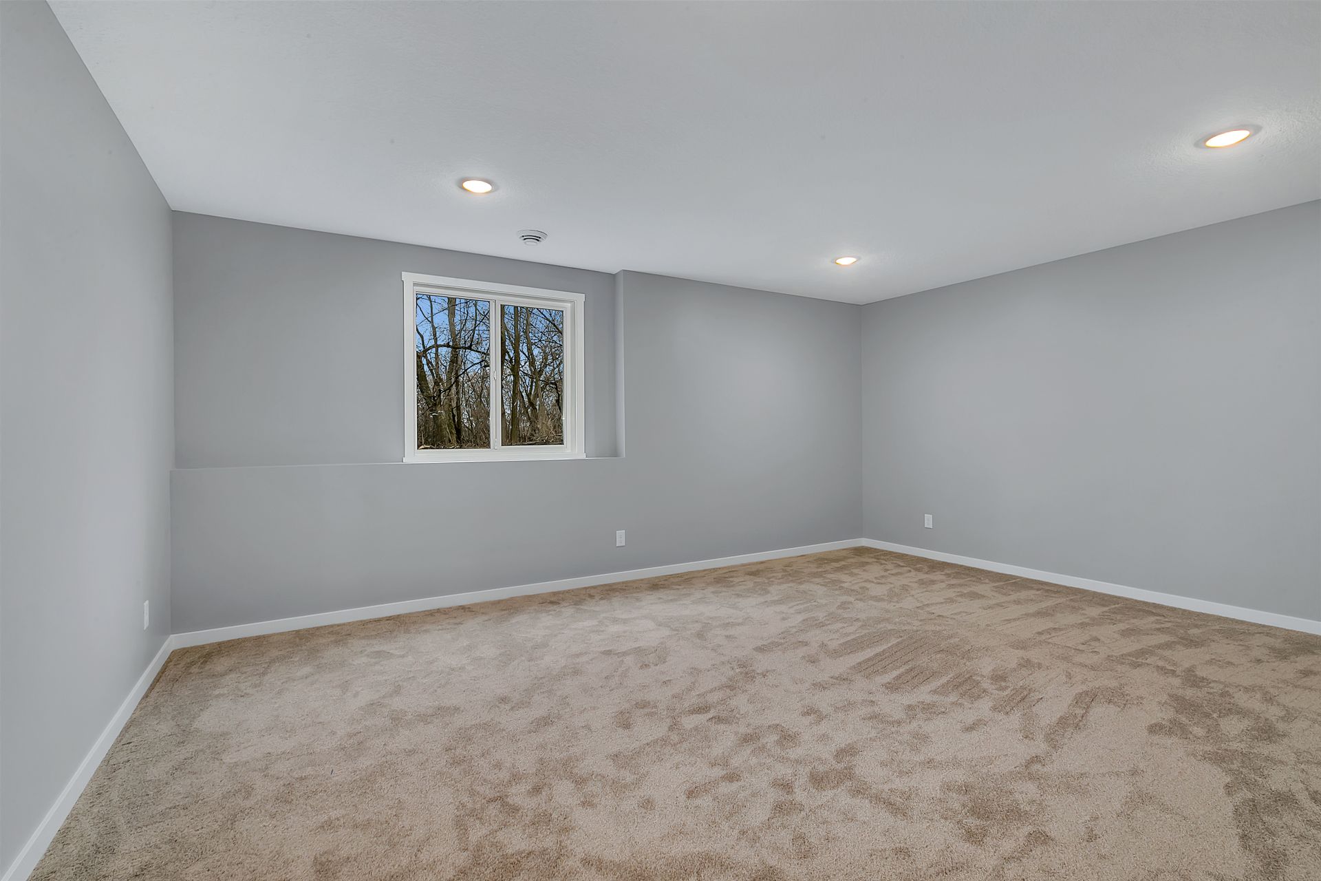 A large empty room with a window and carpet.