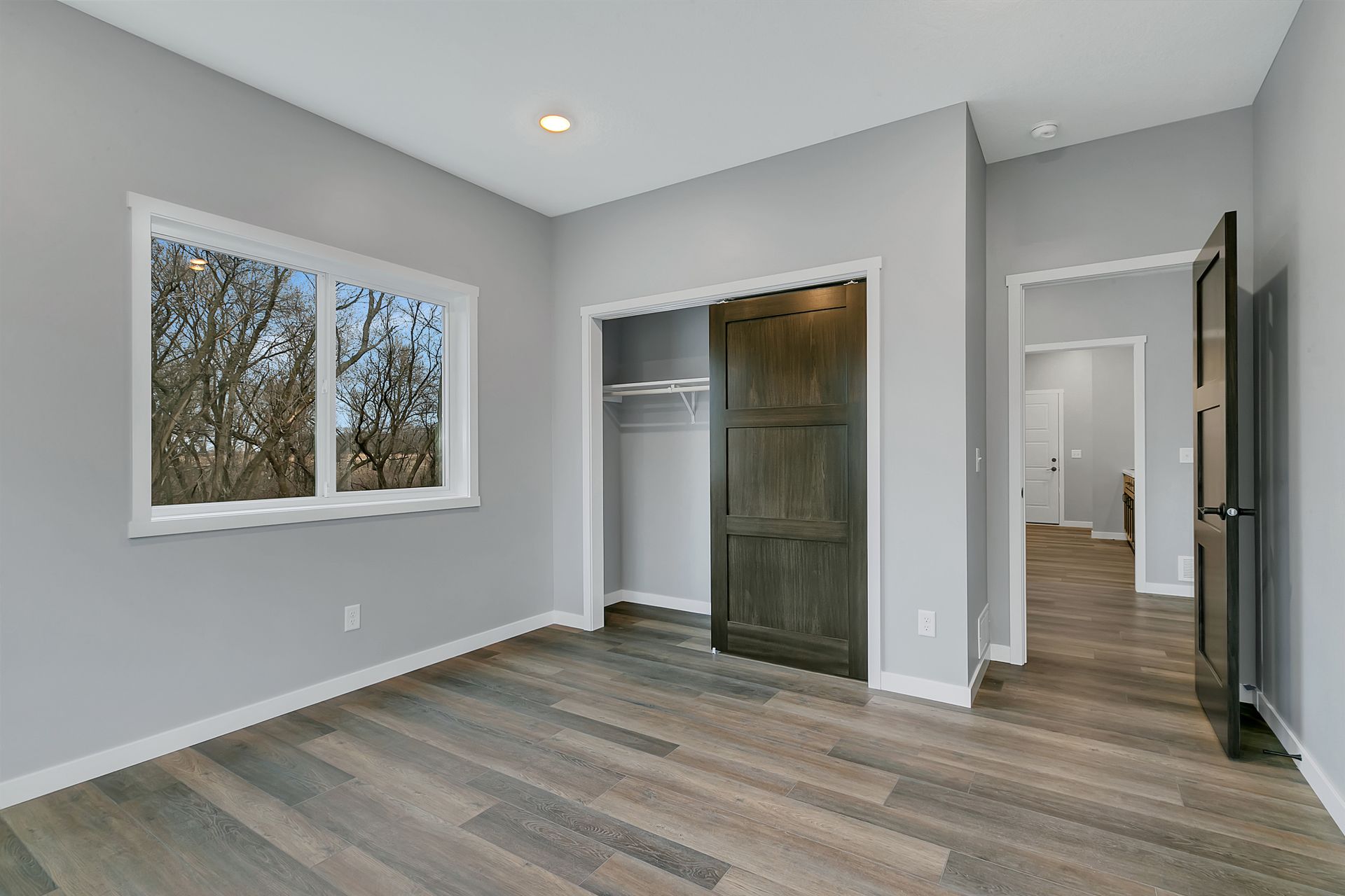 An empty bedroom with hardwood floors and a closet.
