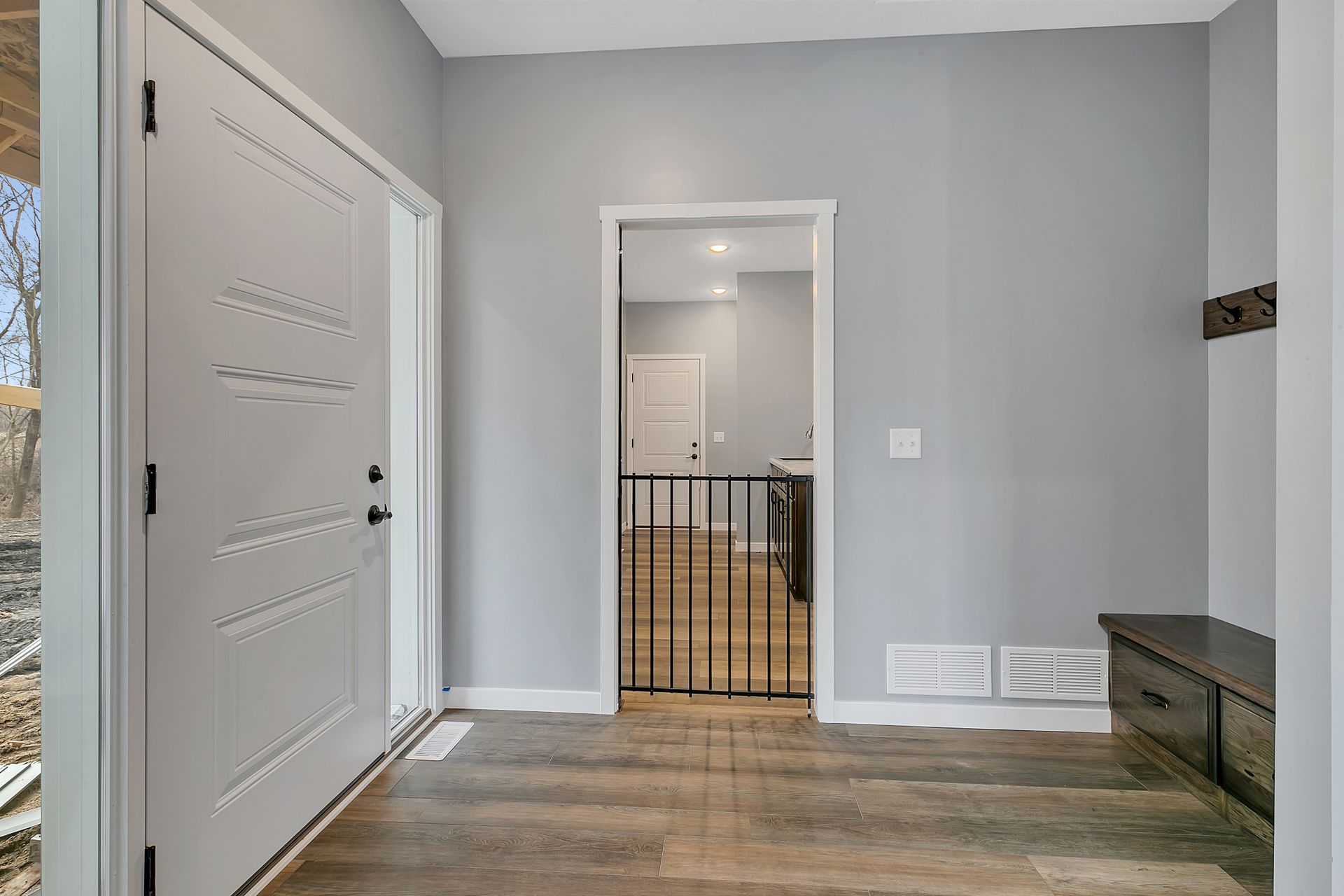 A hallway with a door and a bench in a house.