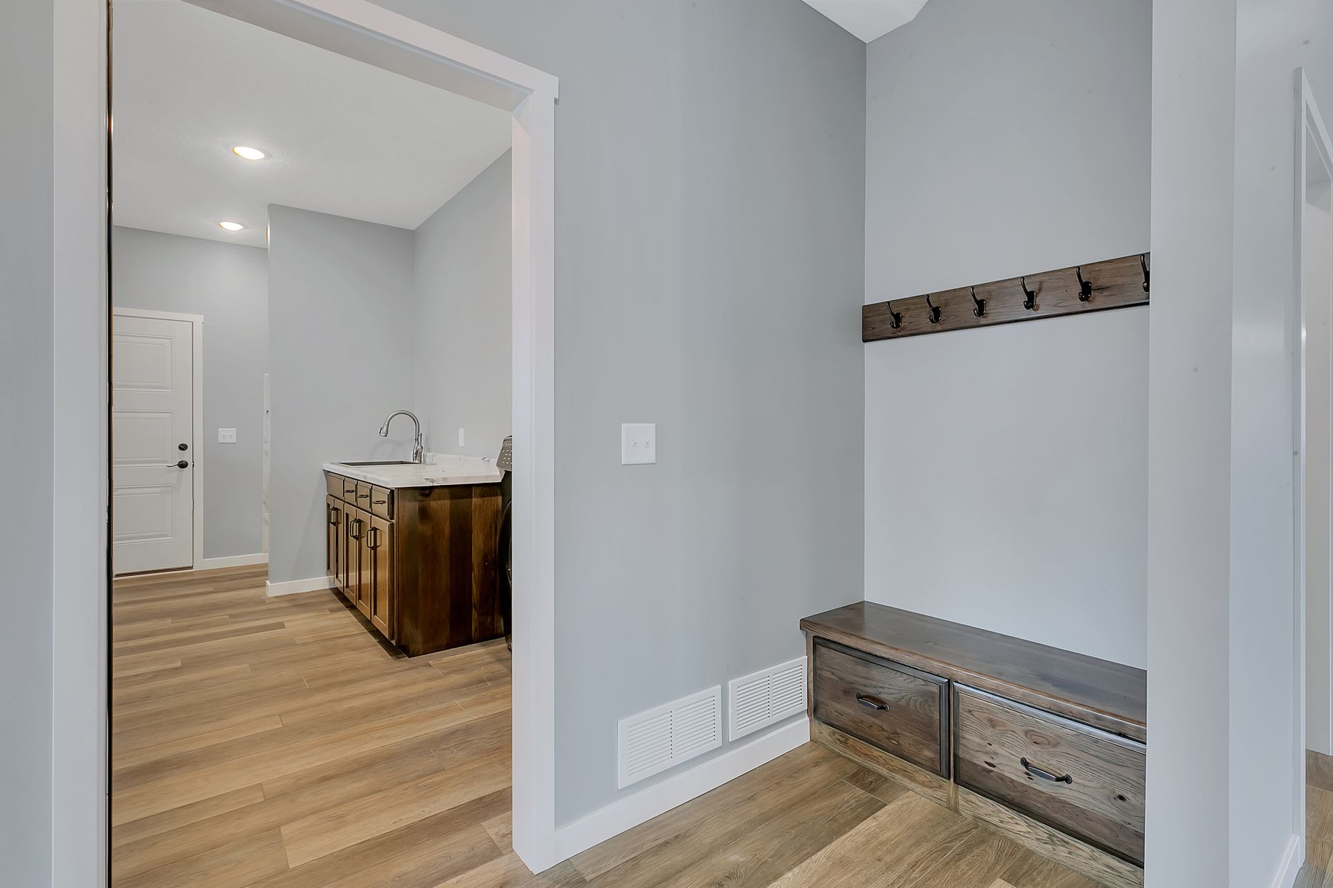 A hallway in a house with a bench and hooks on the wall.