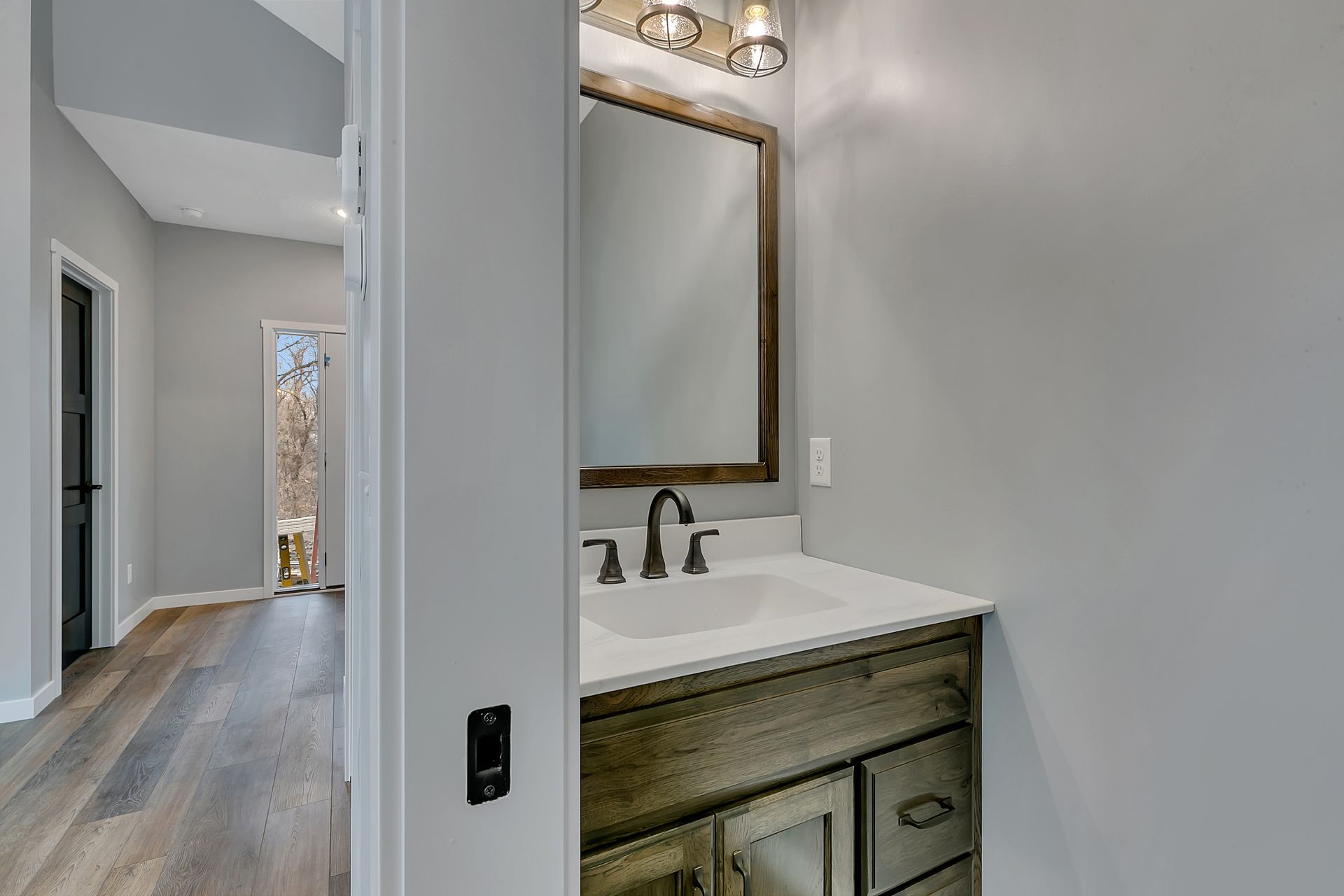 A bathroom with a sink and mirror in a hallway.