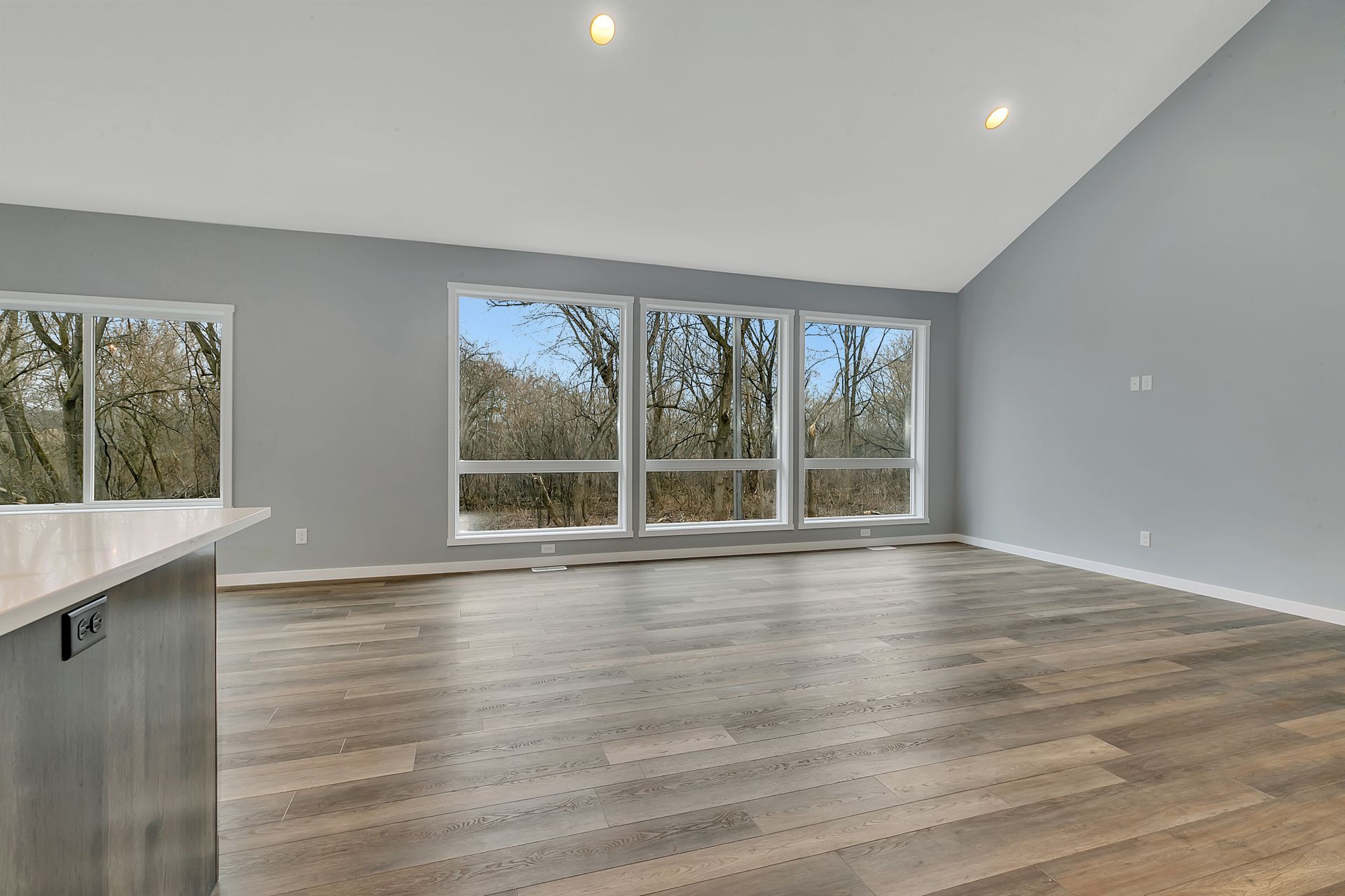 An empty living room with hardwood floors and lots of windows.