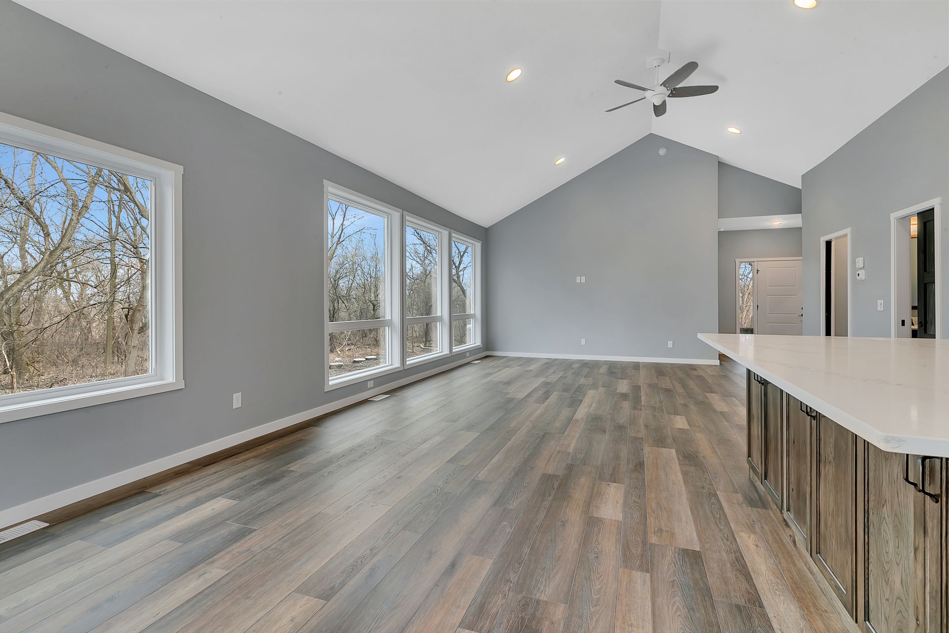A large empty living room with hardwood floors and a ceiling fan.