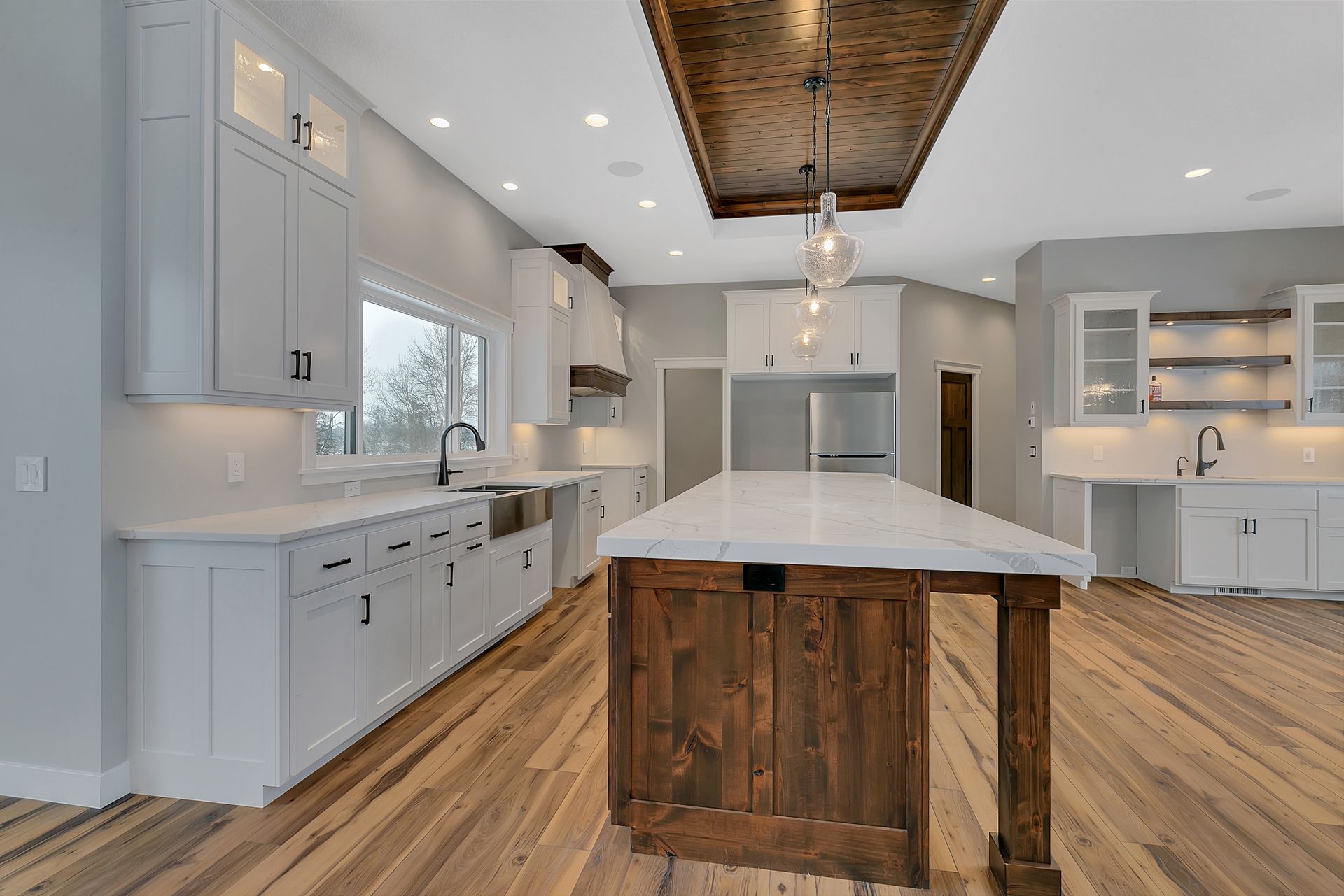A kitchen with white cabinets and a large wooden island.