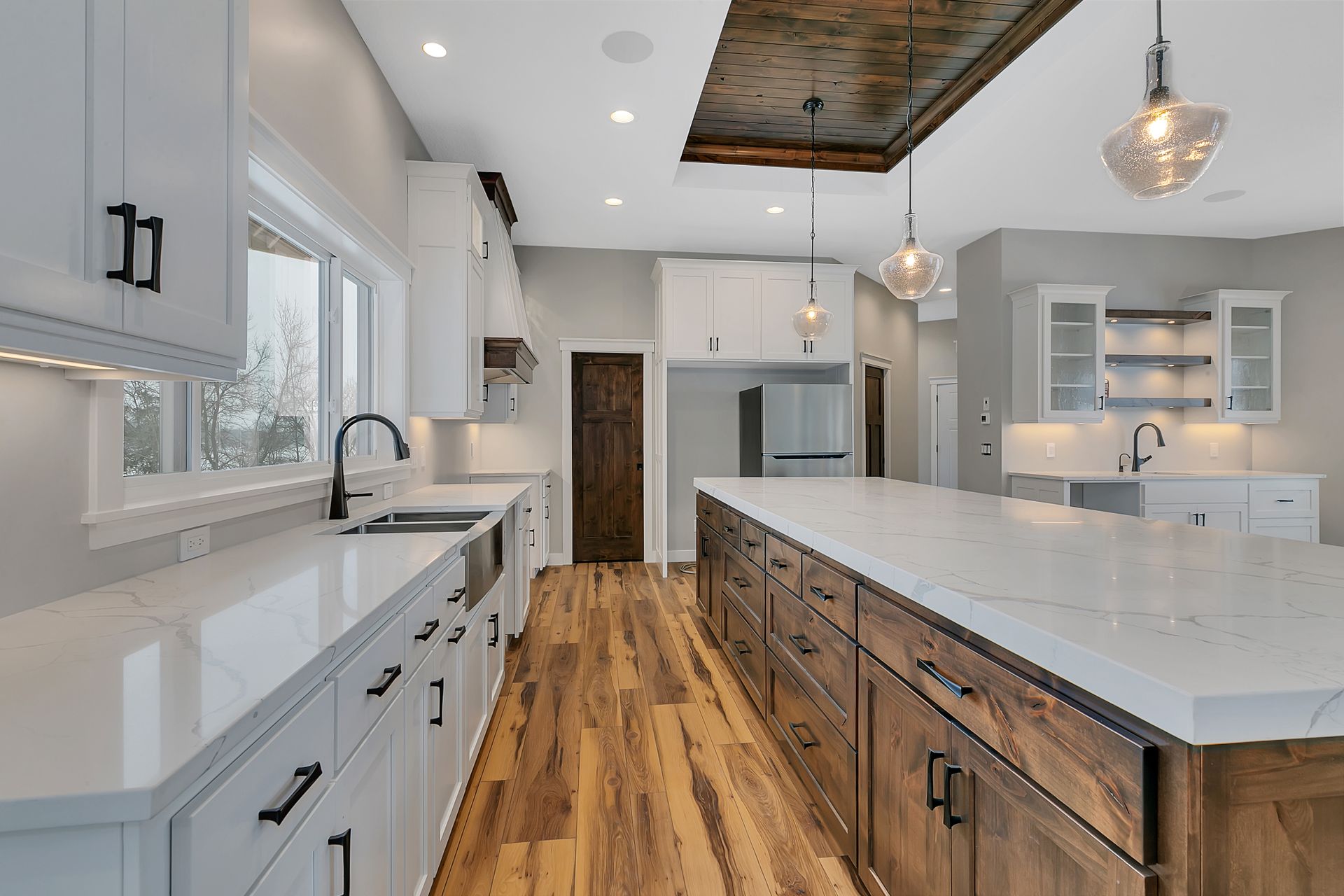 A kitchen with white cabinets and wooden floors and a large island in the middle.